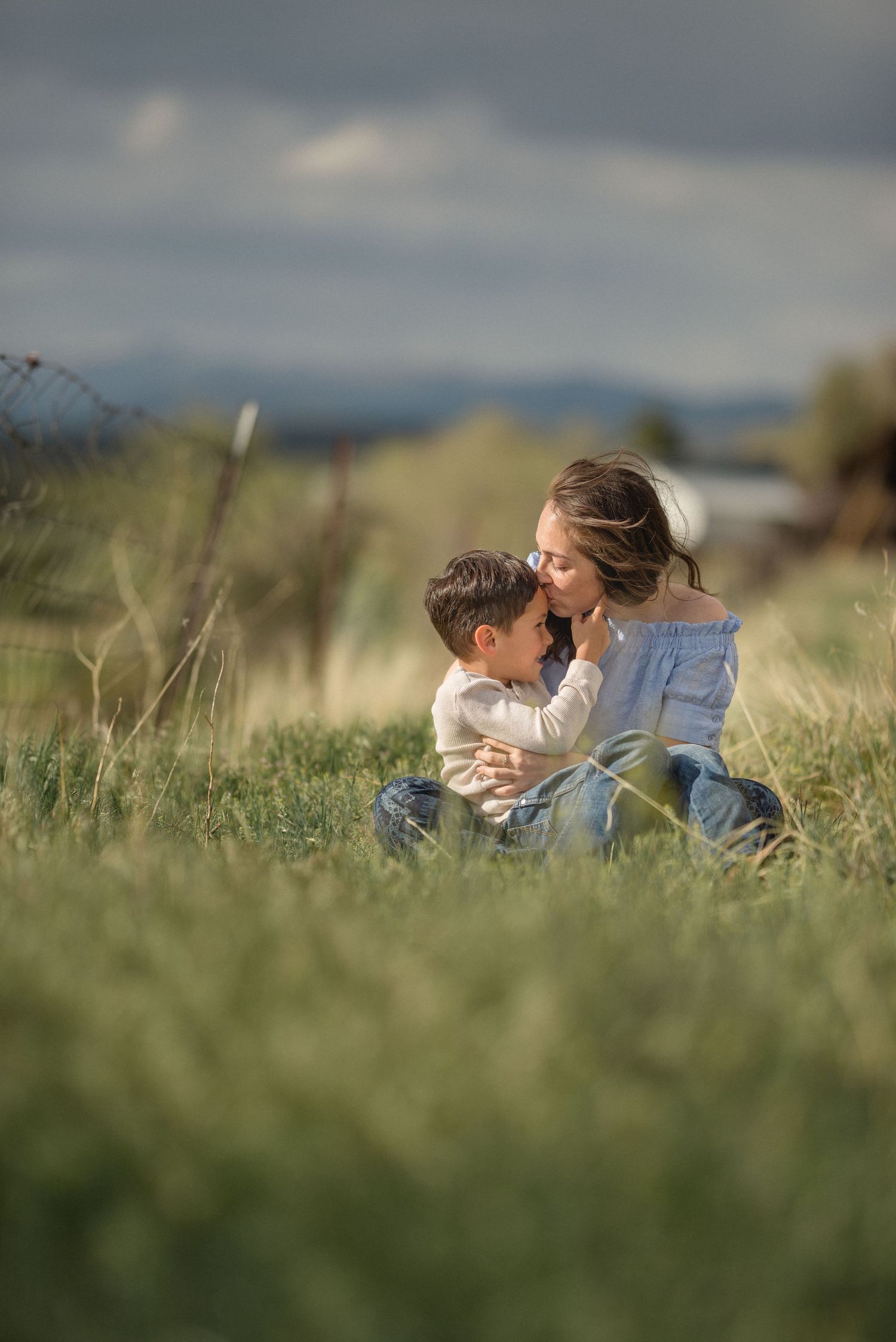 Mom and child sitting on a grassy lawn, sharing a quiet moment — natural light family photo by The Amoras in northern New Mexico.
