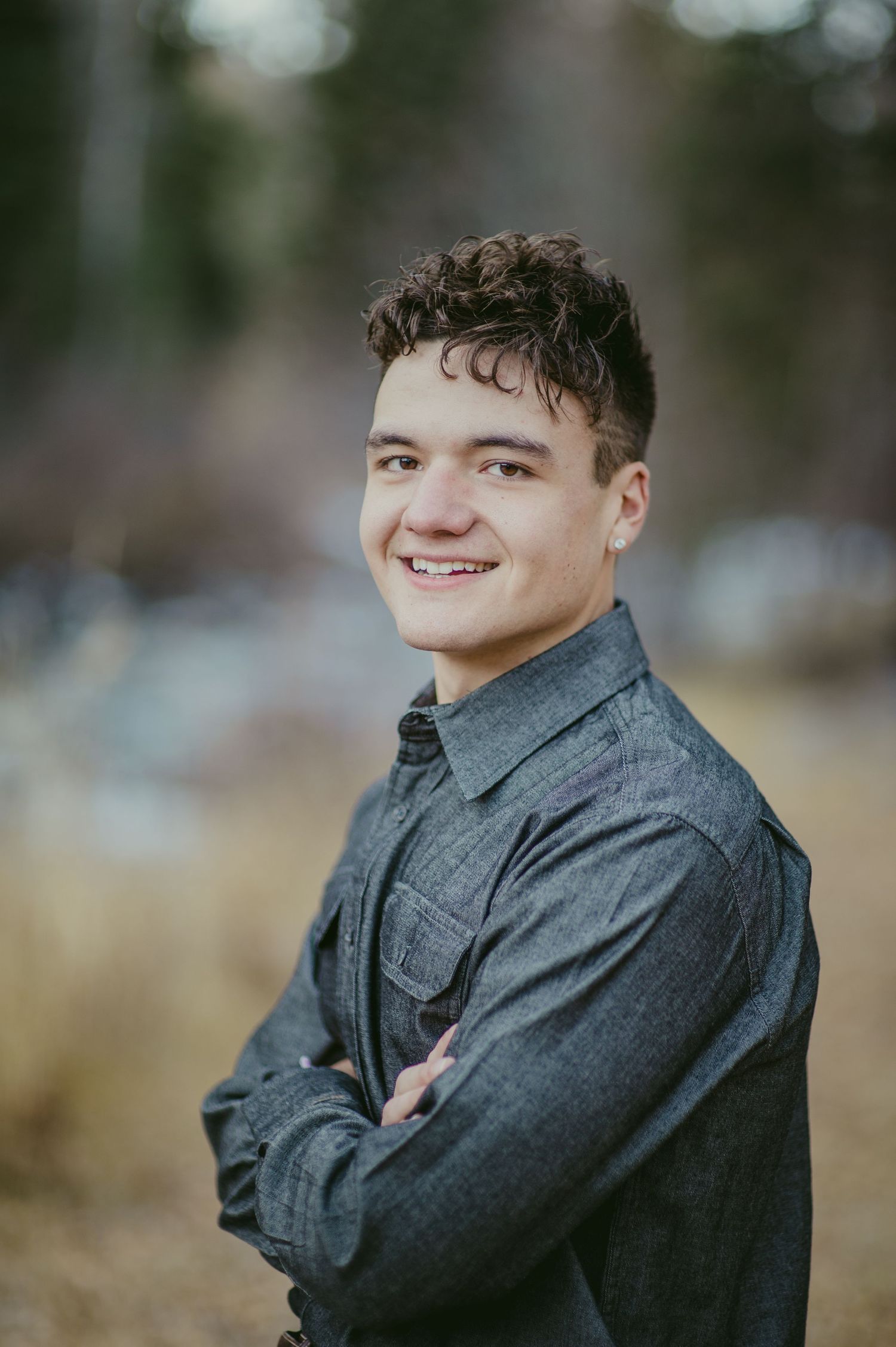 Professional headshot portrait against blurred natural background.