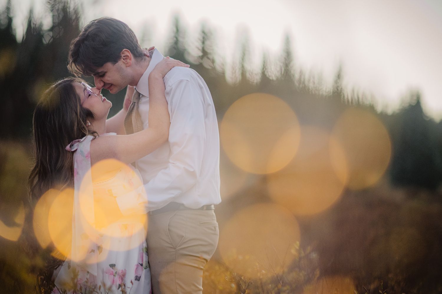 Golden hour engagement portrait with pine trees and soft bokeh in the mountains near Chama, New Mexico.