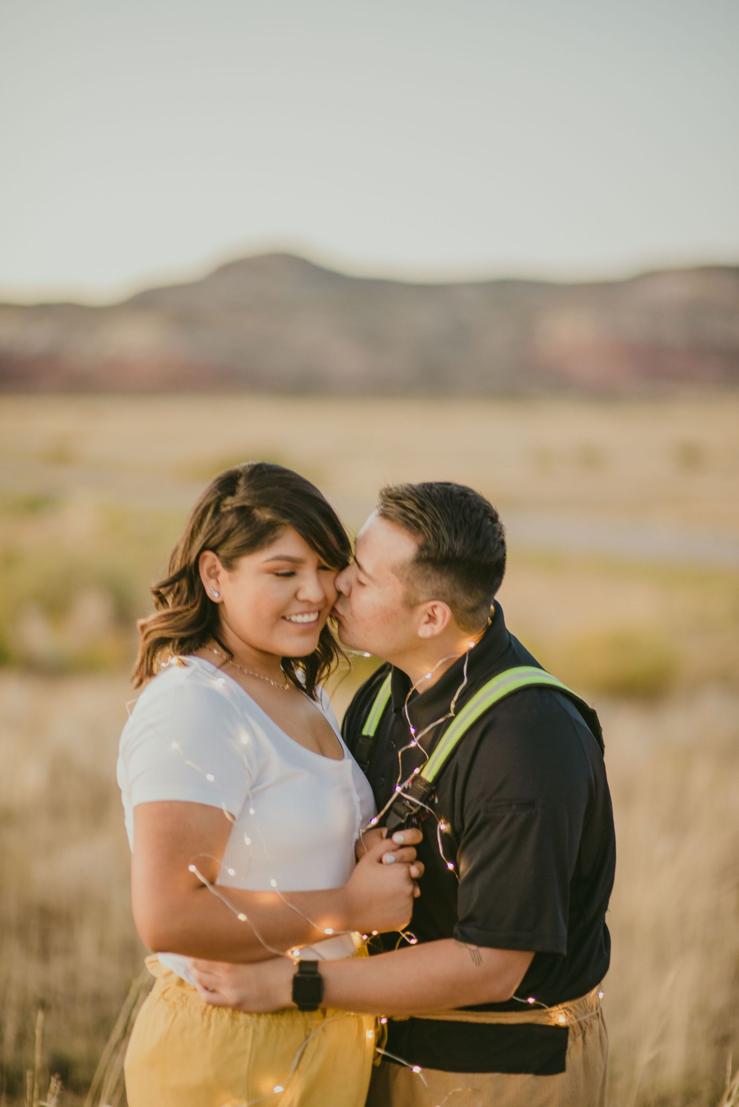 A romantic outdoor photoshoot in a desert landscape with tall grass at golden hour.