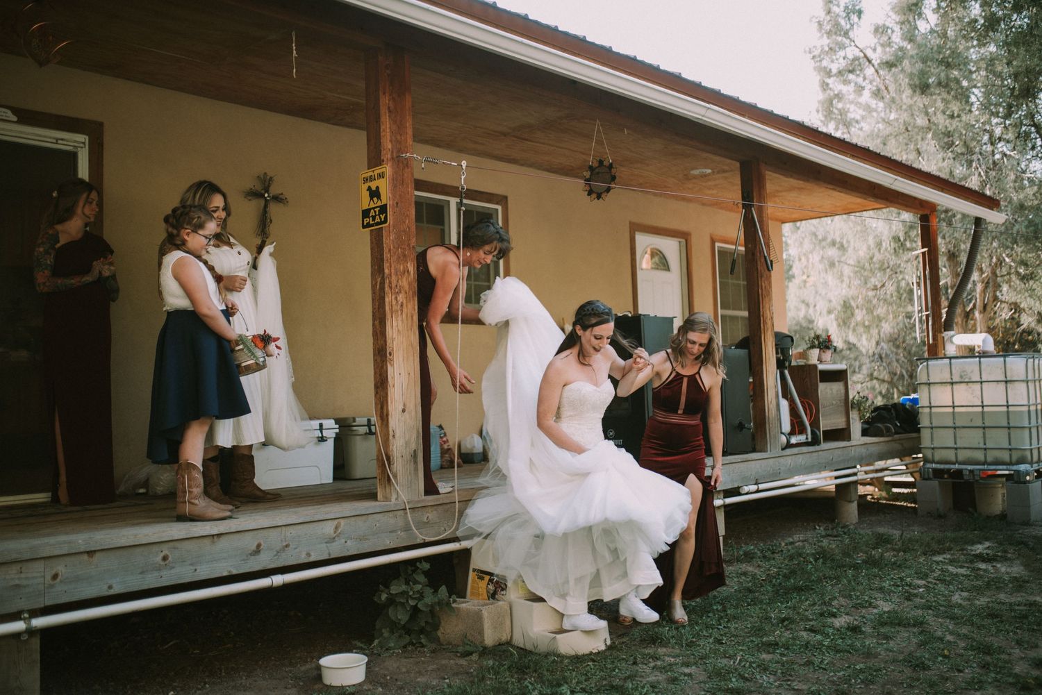 Wedding party relaxing on a rustic porch during an outdoor celebration.