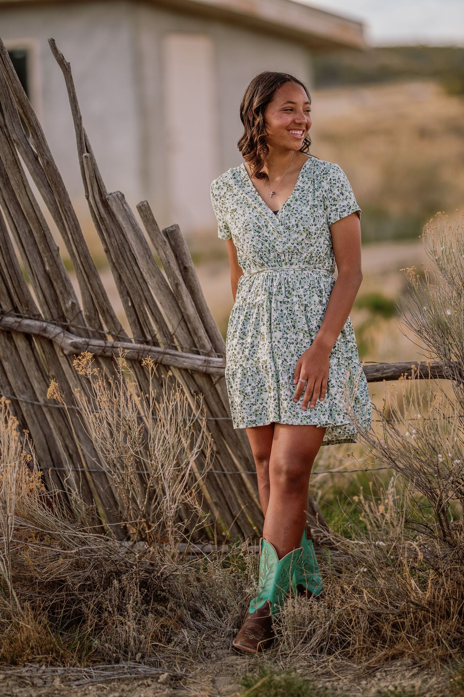 A series of photos showing someone in a floral dress and green rubber boots posing near a rustic wooden fence at sunset.