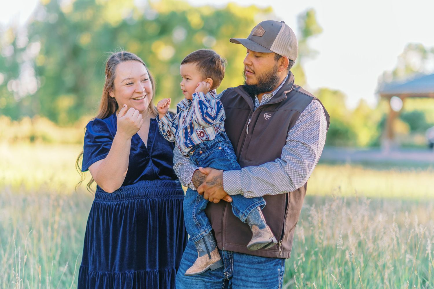 A family shares joyful laughter together while standing in a sunlit meadow on a warm autumn day.