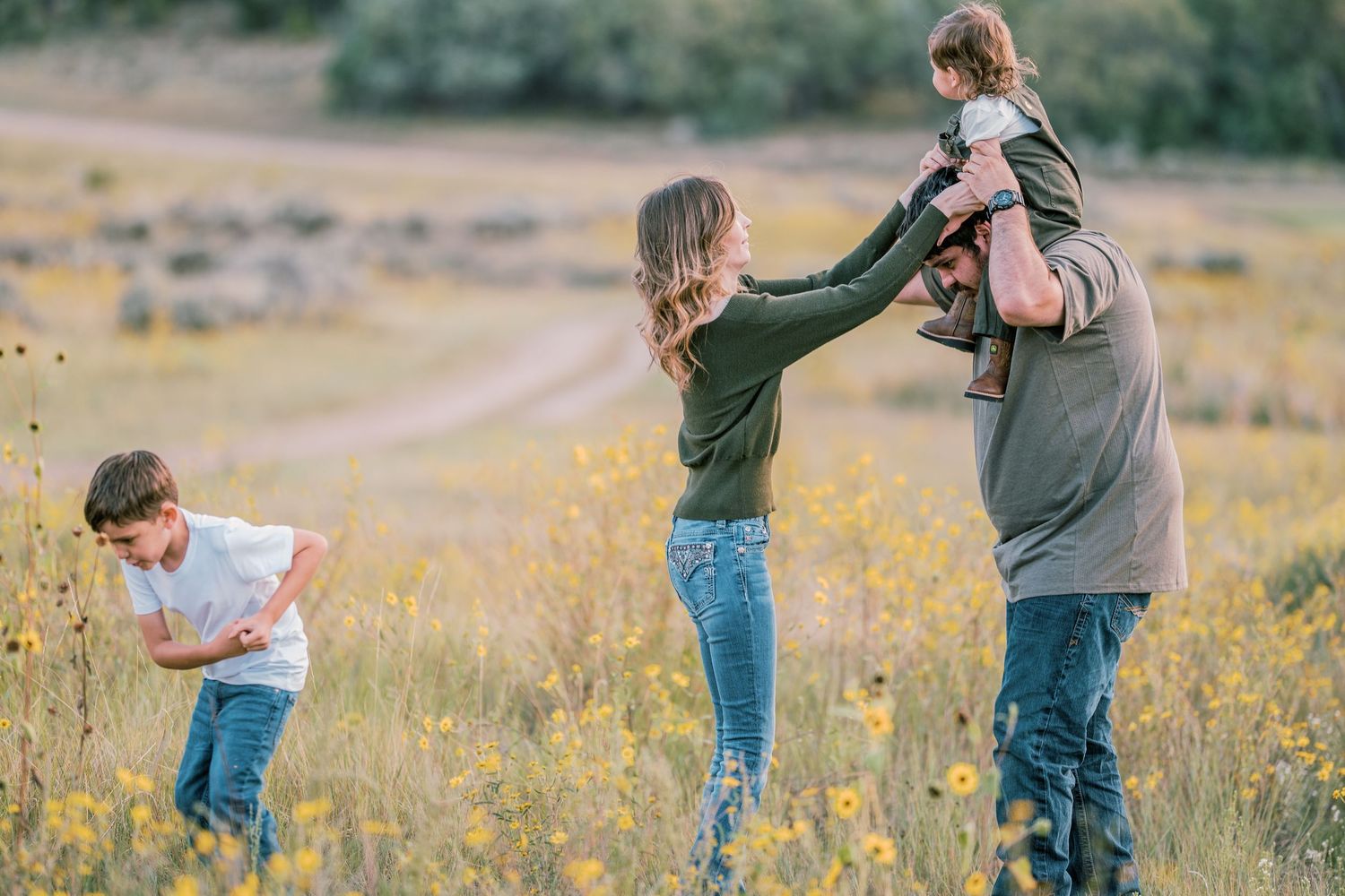 Candid family moment captured in a golden wildflower field during sunset.