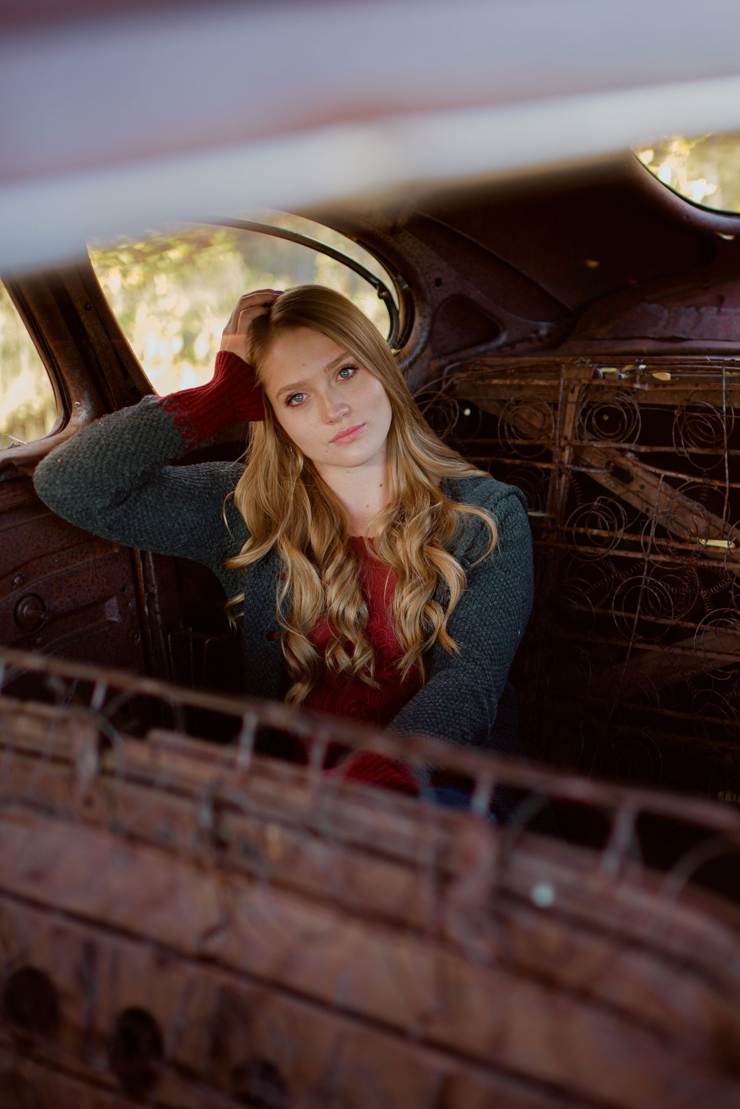 Portrait photoshoot in moody lighting with dramatic shadows against wooden backdrop of barn interior.