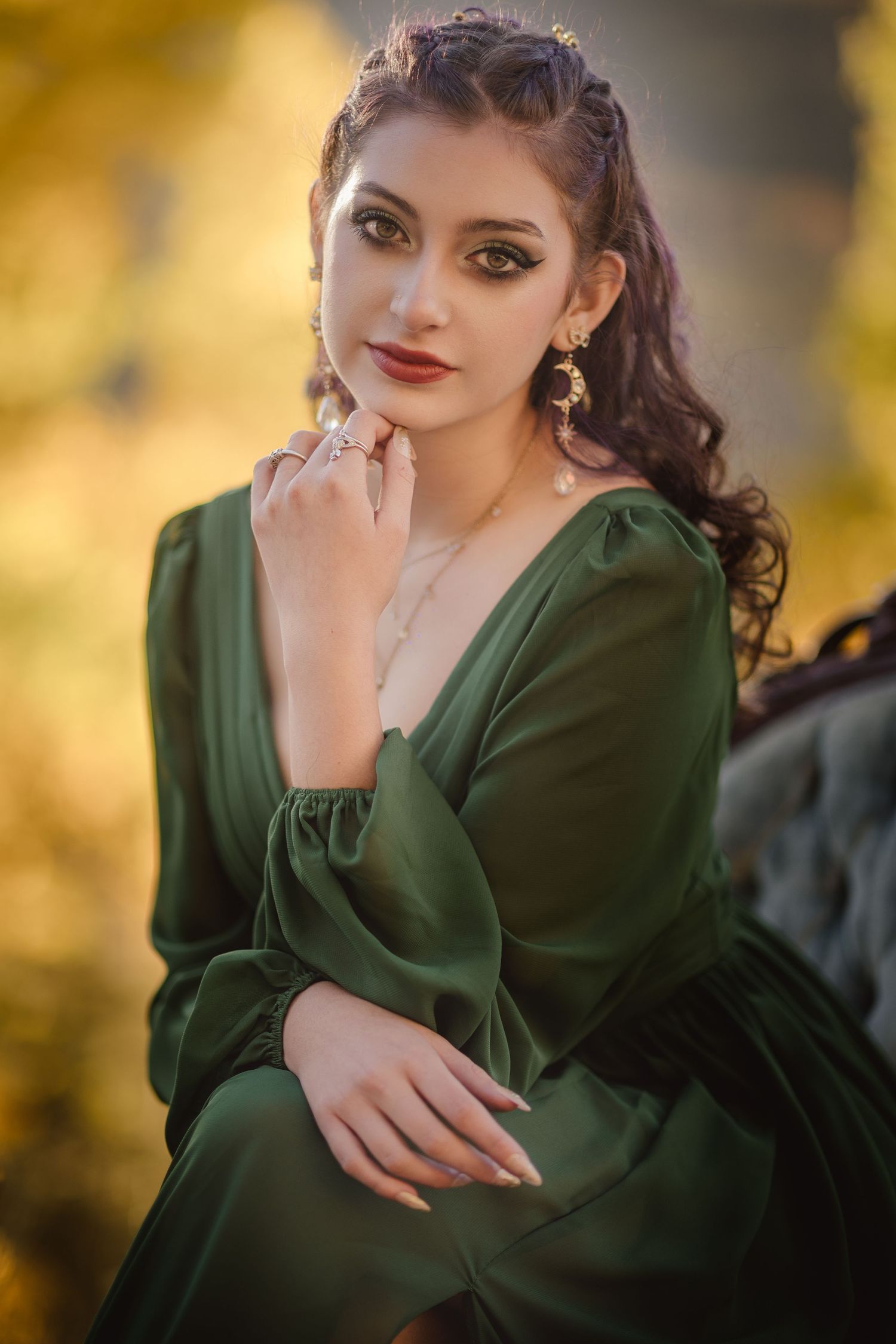 A woman in a dark green vintage-style dress poses elegantly against a golden bokeh background.