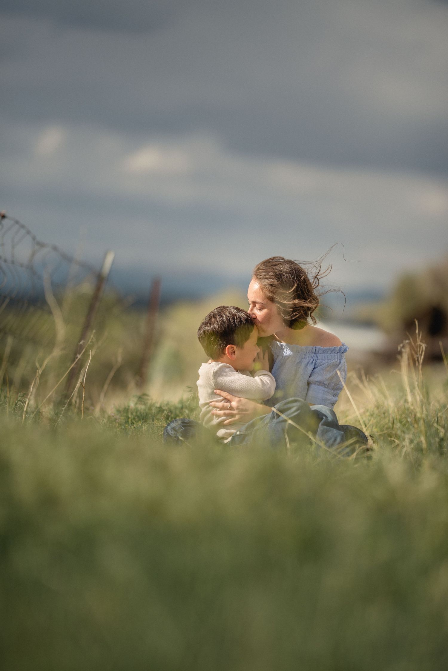 Someone lies peacefully in a grassy meadow on a cloudy day, photographed in a dreamy panoramic sequence.