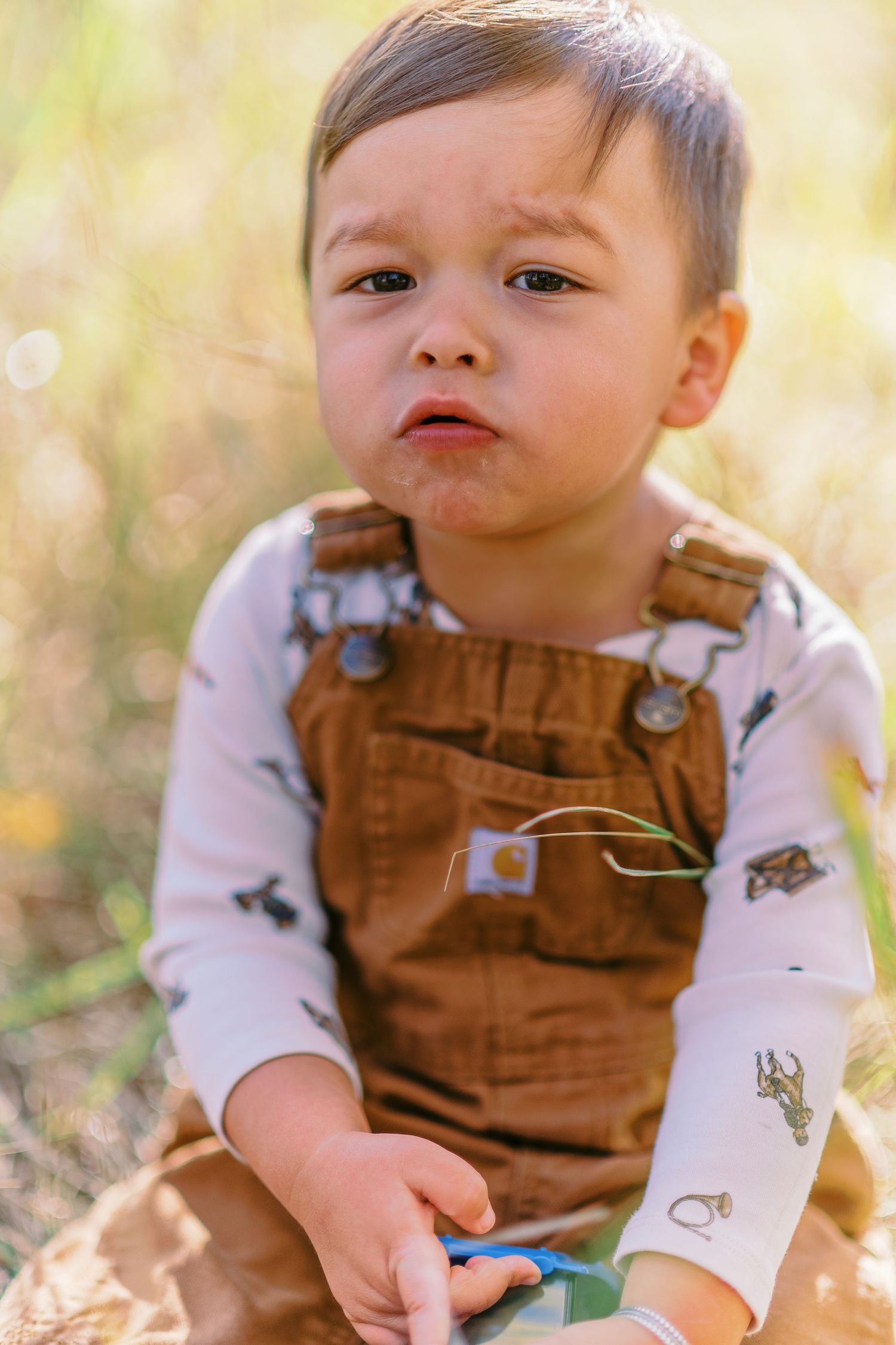 A series of outdoor portraits showing a small child wearing brown overalls and a white long sleeve shirt in natural lighting.