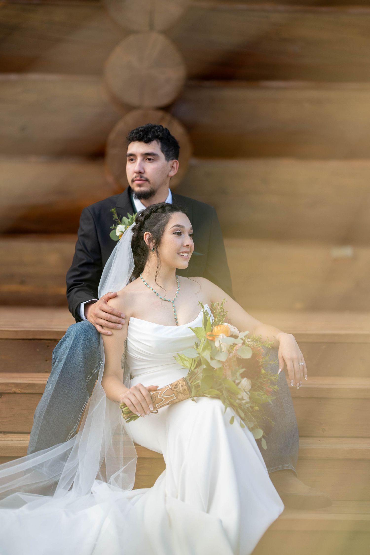 Elegant wedding portrait against a rustic log cabin wall.