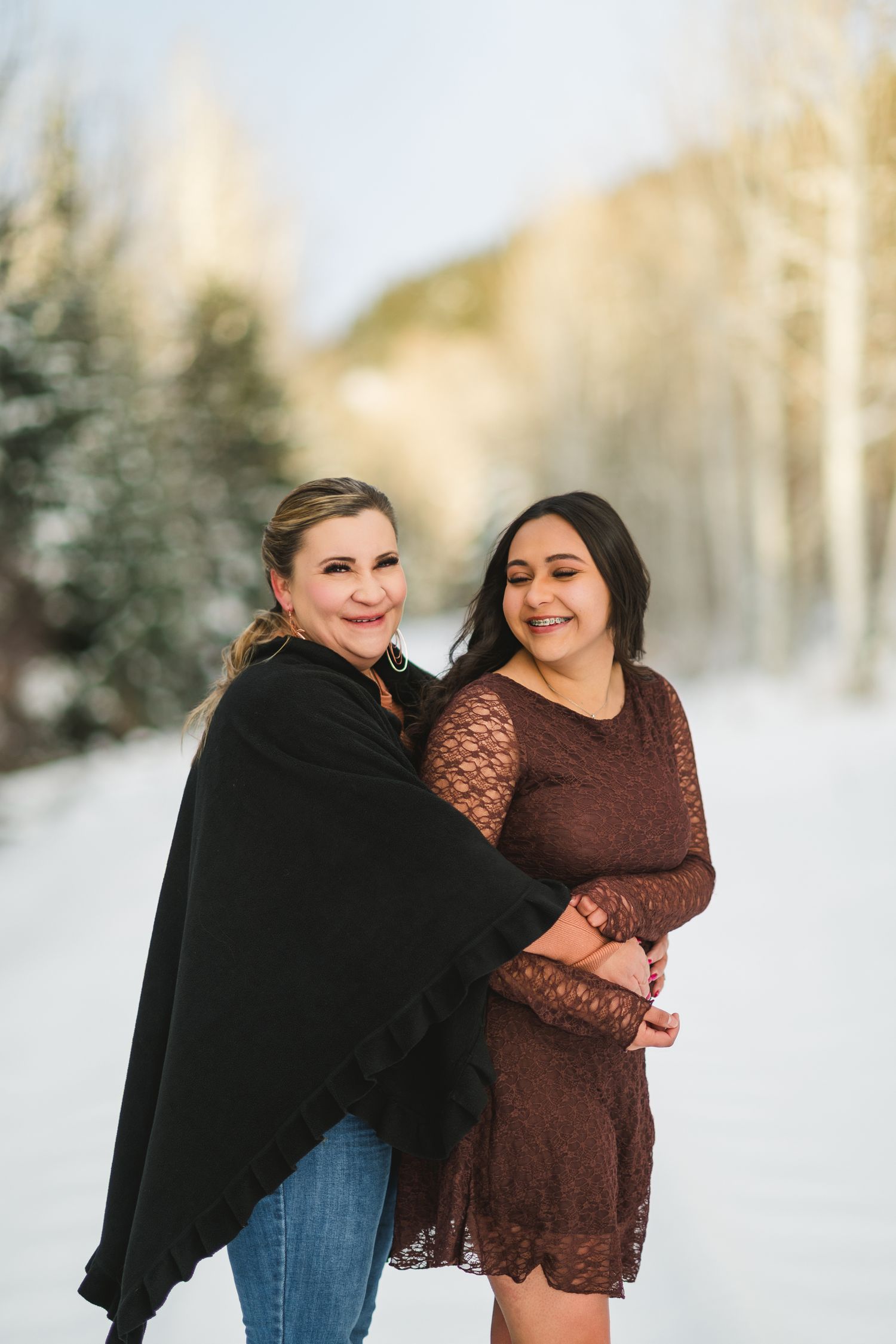 Two people share a joyful moment together in a snowy winter landscape wearing casual attire.