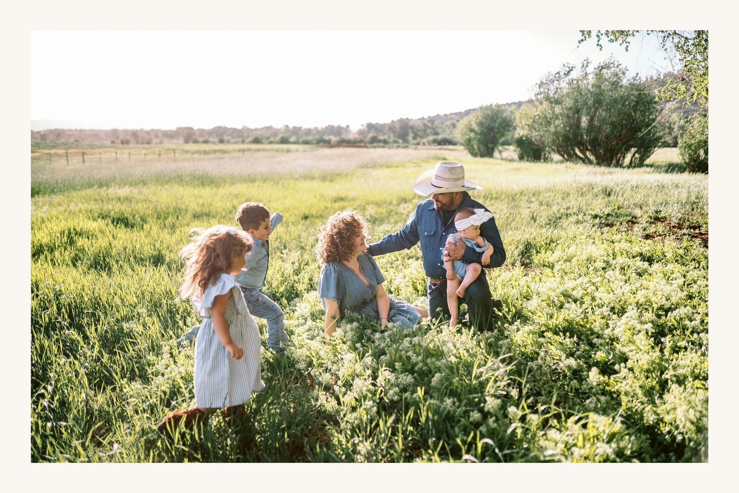 Family gathering in a lush green field on a sunny day.