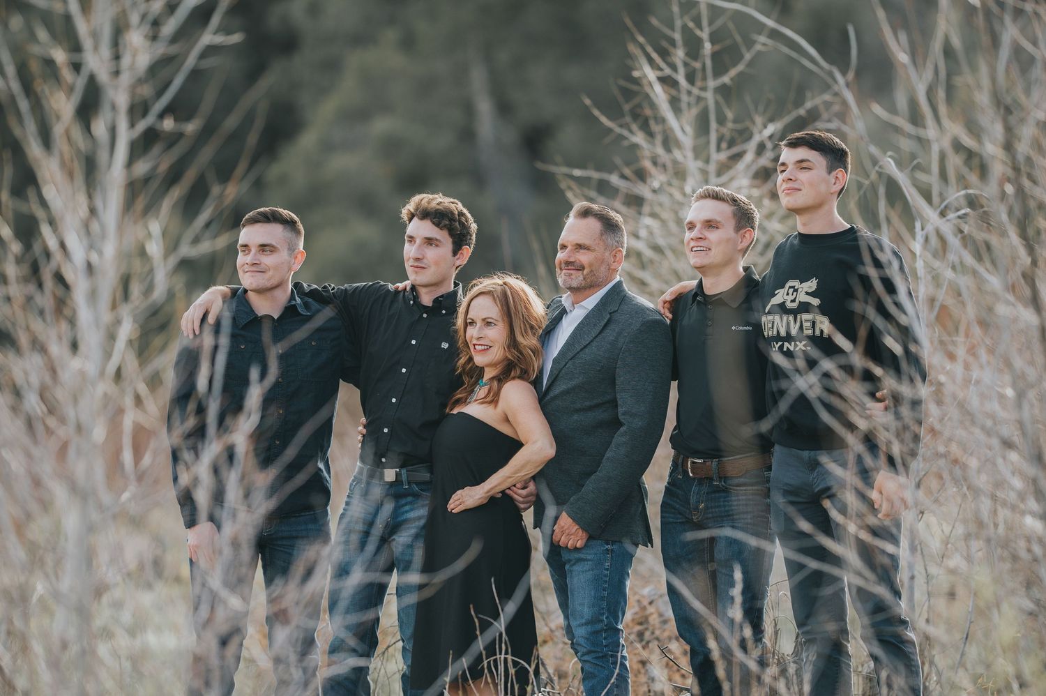 Parents and their four grown sons walking together through a sunlit field near Santa Fe — natural, heartfelt moment by The Amora