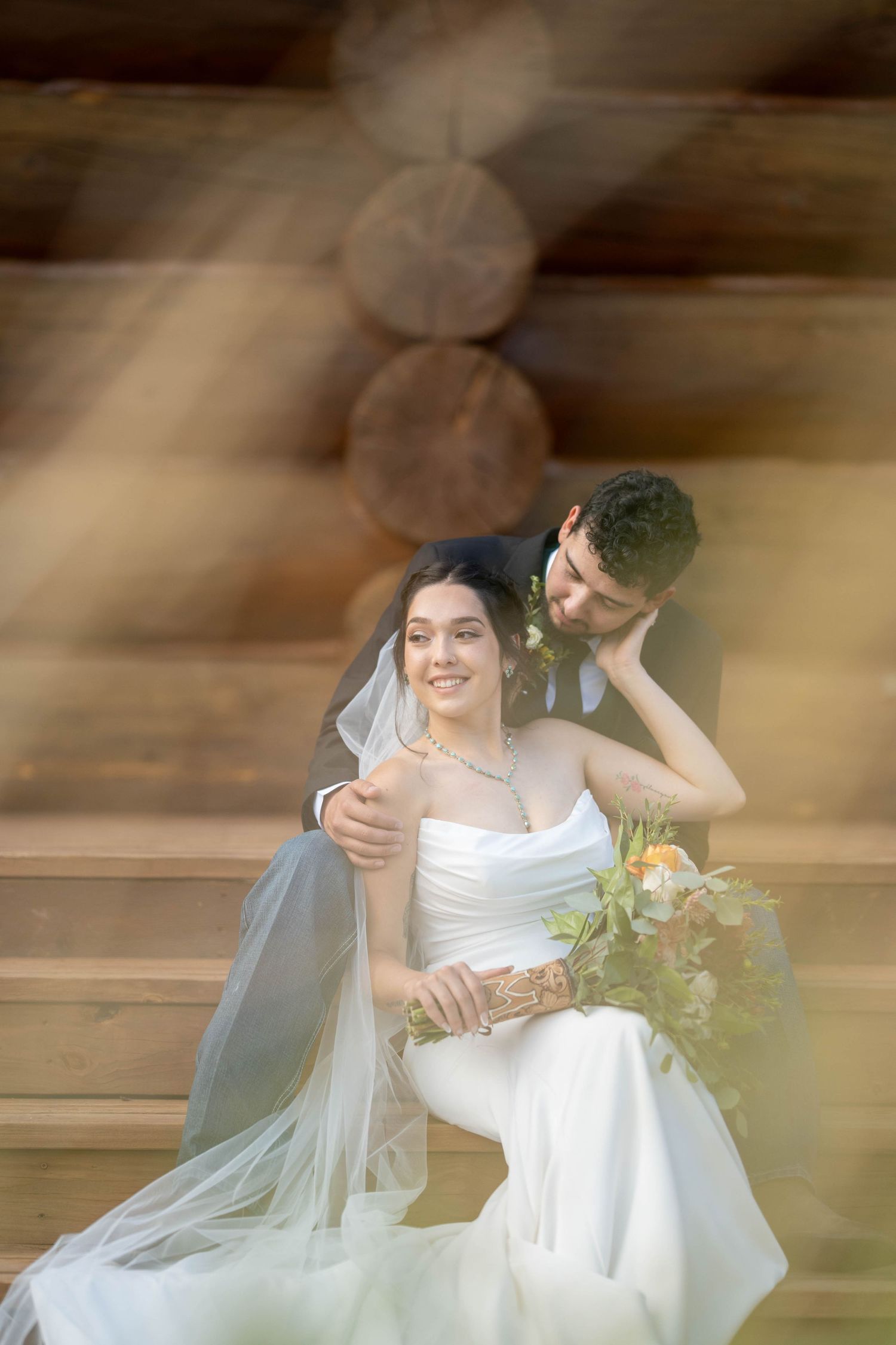 Soft-focus wedding portrait in a rustic wooden setting with natural light.