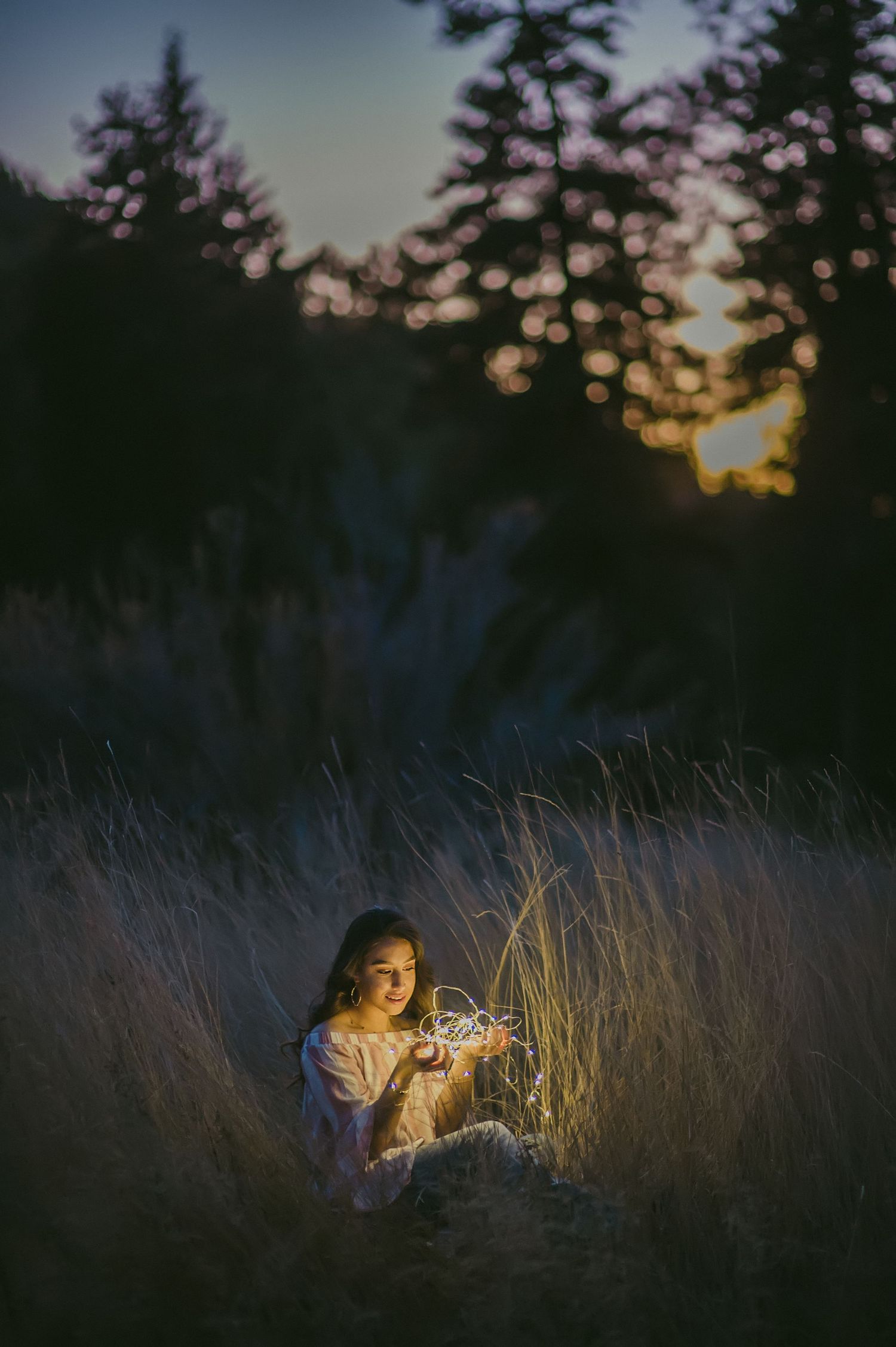 Atmospheric evening portrait in tall grass with dramatic sunset lighting.