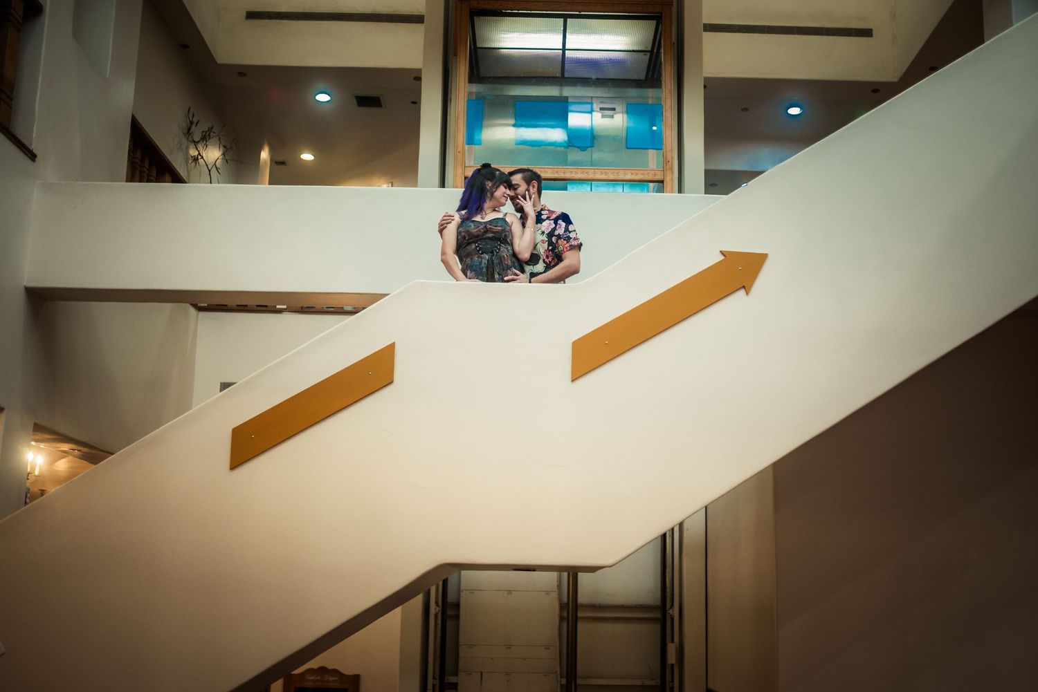 People gathered on a white staircase with gold arrow signs in a modern building interior.