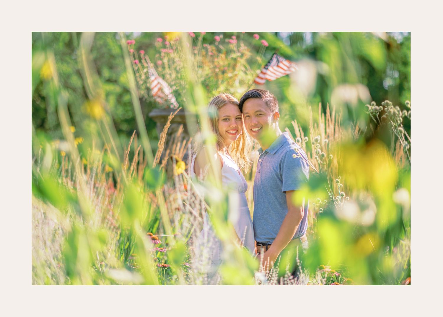 A romantic summer engagement photo session in a wildflower meadow at sunset with soft golden light shining through tall grass.