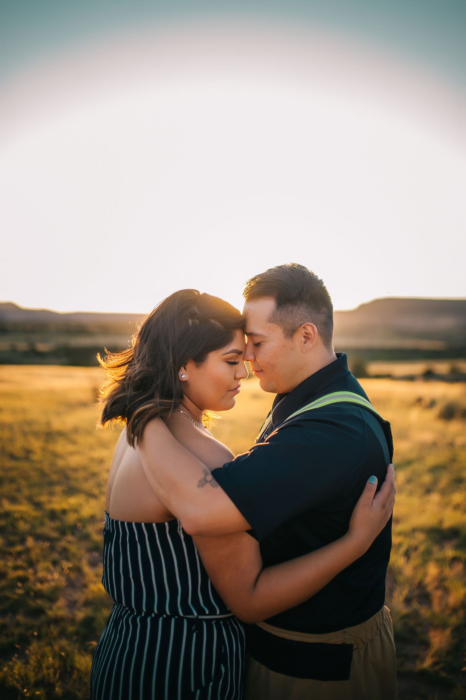 A couple sharing intimate moments in a field during golden hour.