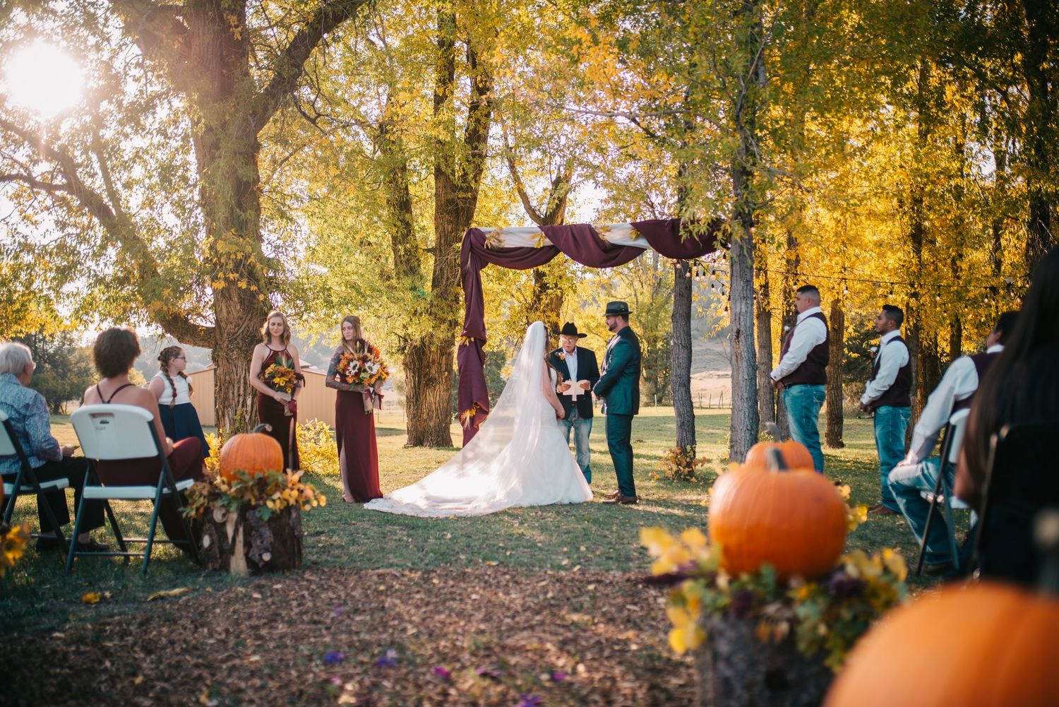 Beautiful fall wedding photos with autumn leaves and pumpkin decor in the background.