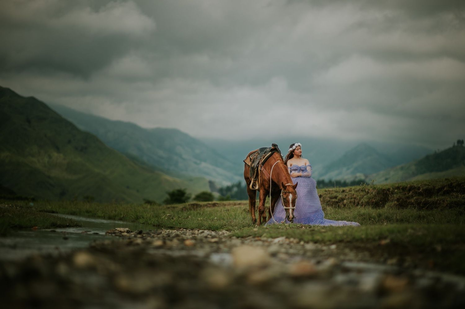 Dramatic mountain landscape with horse and rider silhouetted against stormy skies.
