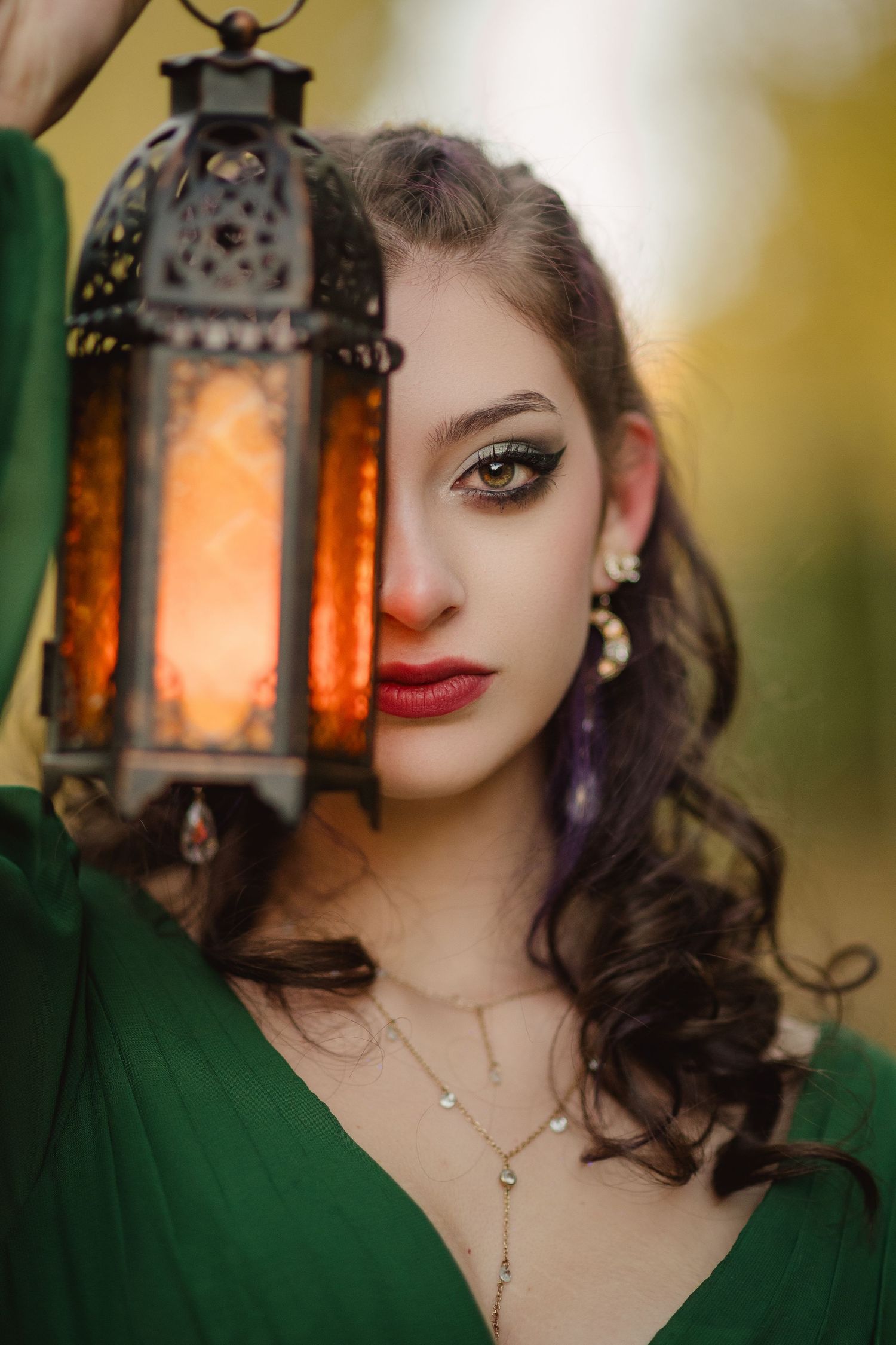 A series of vintage-style photos with an ornate glowing lantern and emerald green clothing in warm ambient lighting.