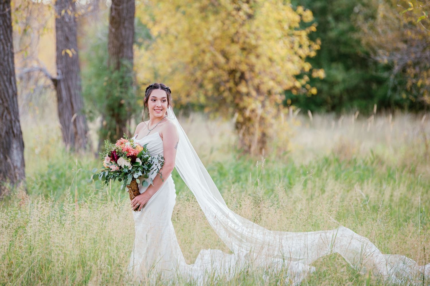 Classic bridal portrait in a sunlit meadow with flowing veil and autumn colors.
