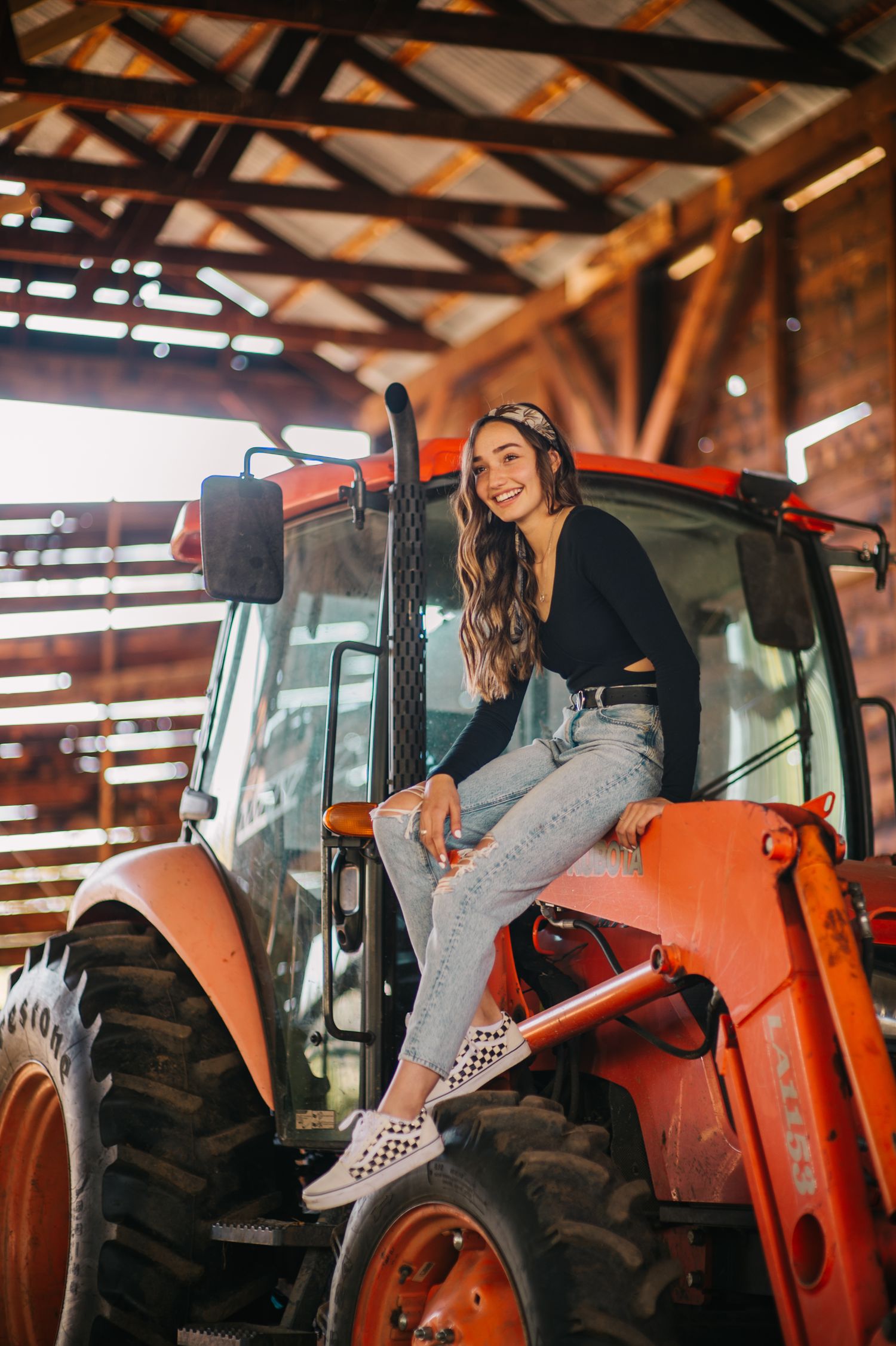Artistic shots of person sitting on vintage orange tractor in rustic barn environment.