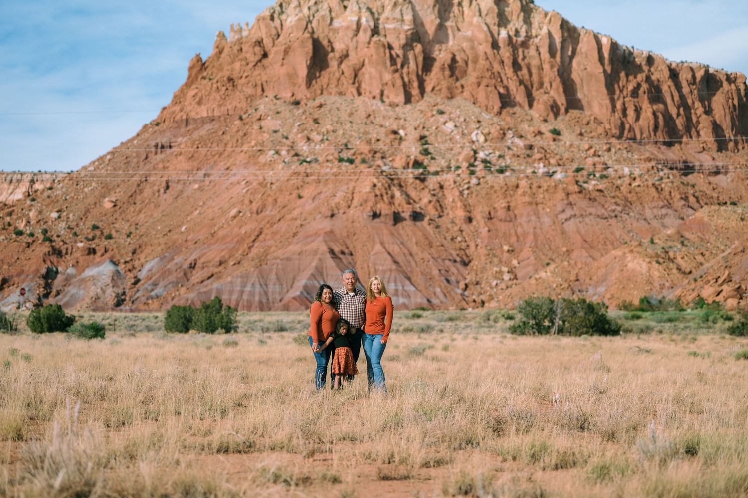 People walking and exploring along scenic hiking trails near tall red rock formations in the desert landscape.
