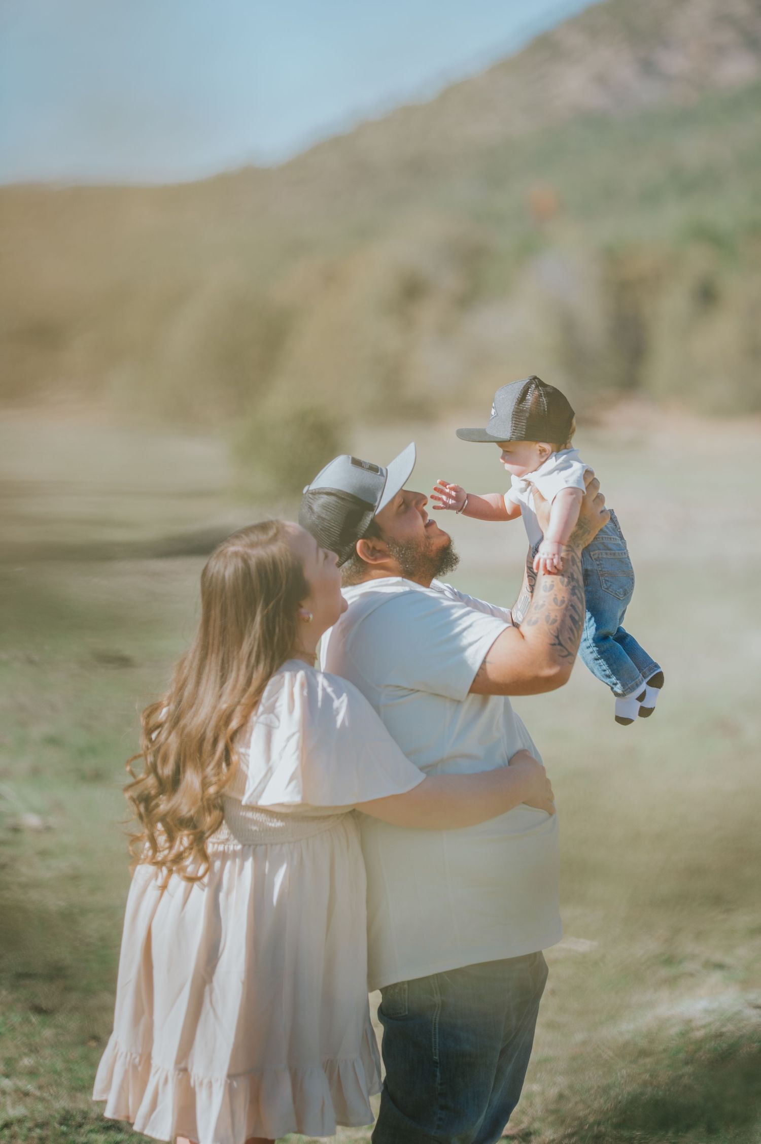 Family of three embracing in the open shrubland near Santa Fe, New Mexico — serene and warm image by The Amoras.