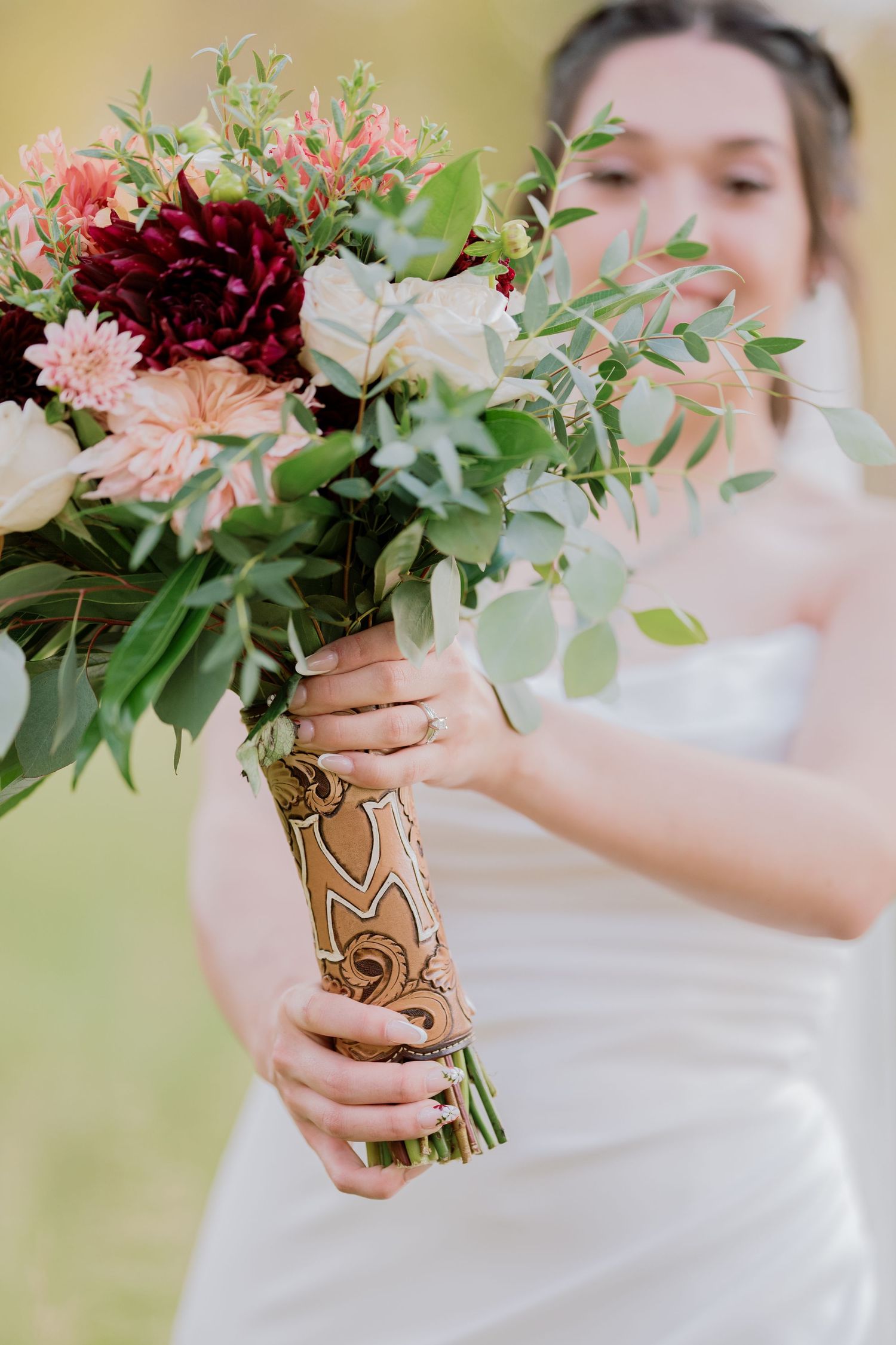 Close-up of a stunning bridal bouquet with burgundy and pink flowers wrapped in decorative paper.