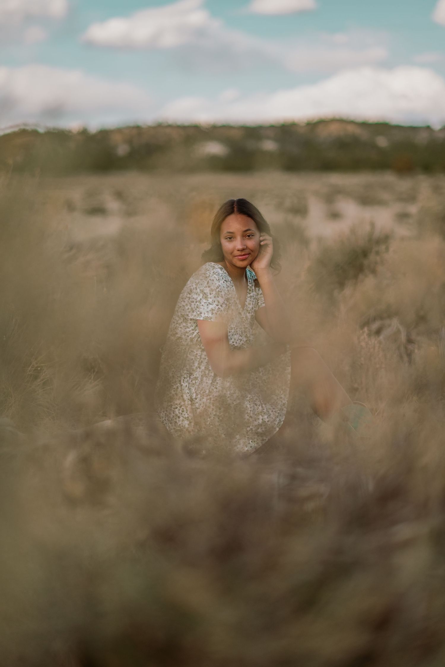 Senior girl sitting in light green grass during a soft afternoon session in northern New Mexico — portrait by Quiet Light by The Amoras.