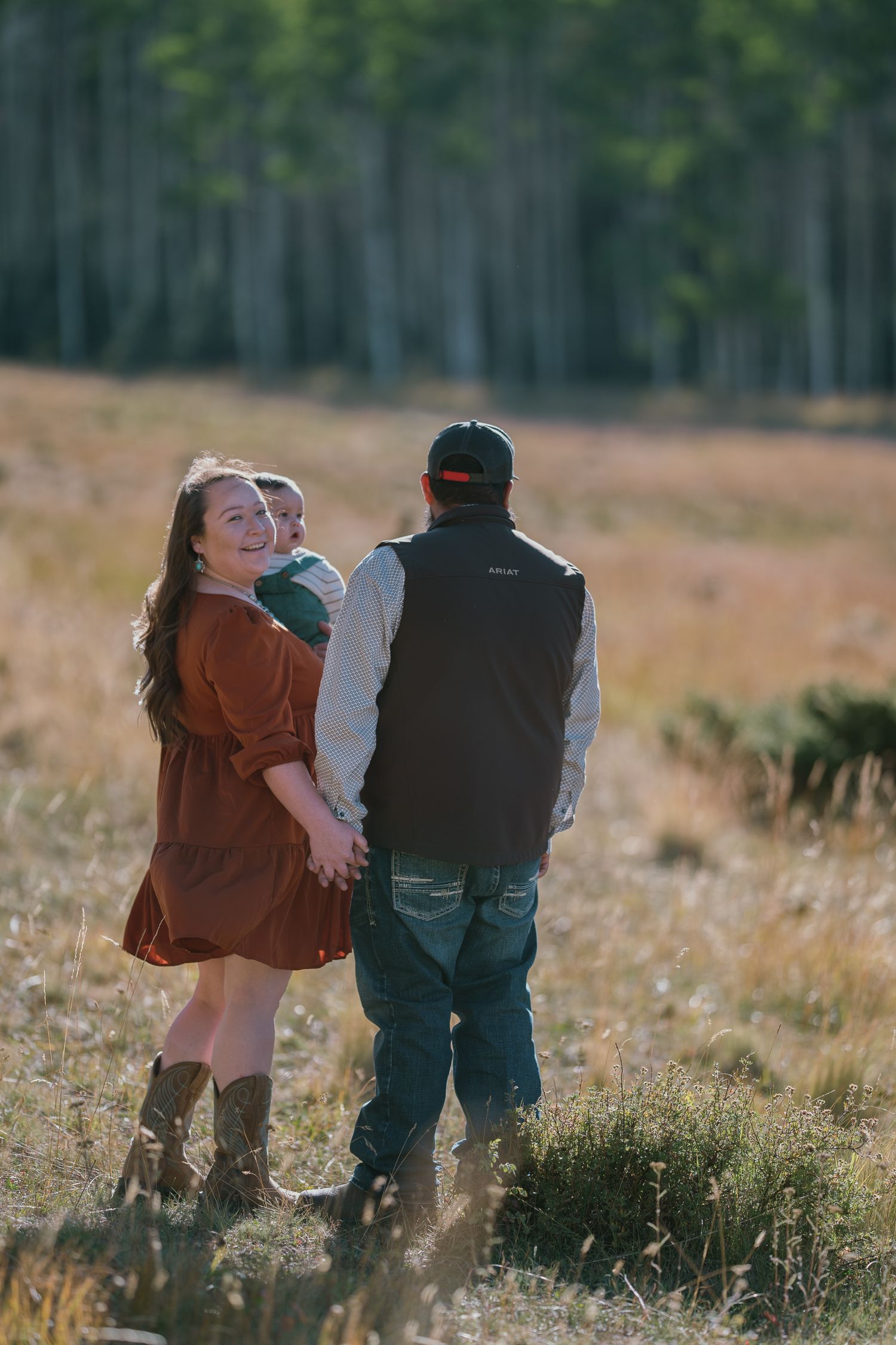 A couple enjoying a playful moment together in a sunlit field with trees.