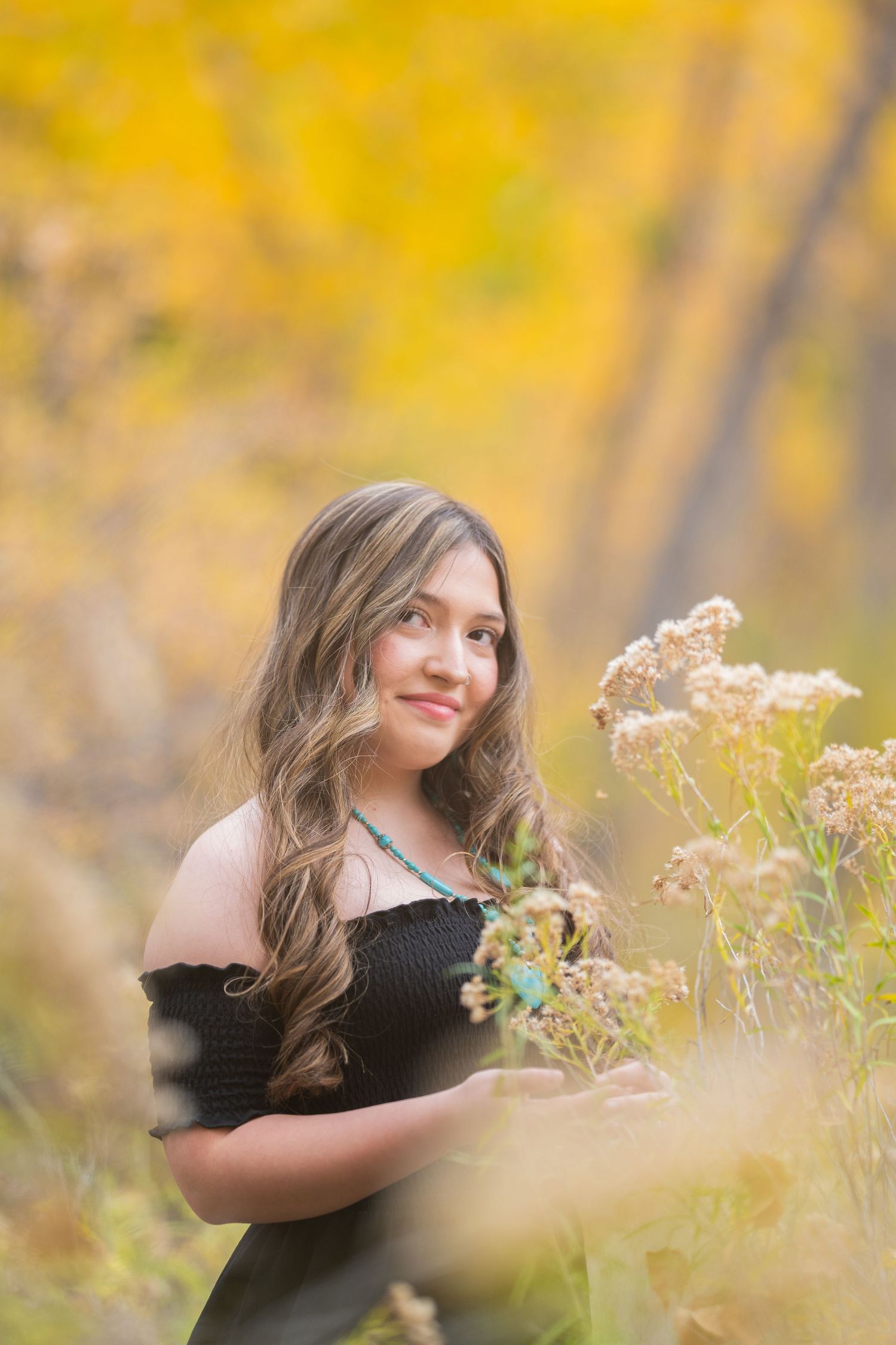 A photoshoot captured in a field of wildflowers during golden hour with autumn colors in the background.