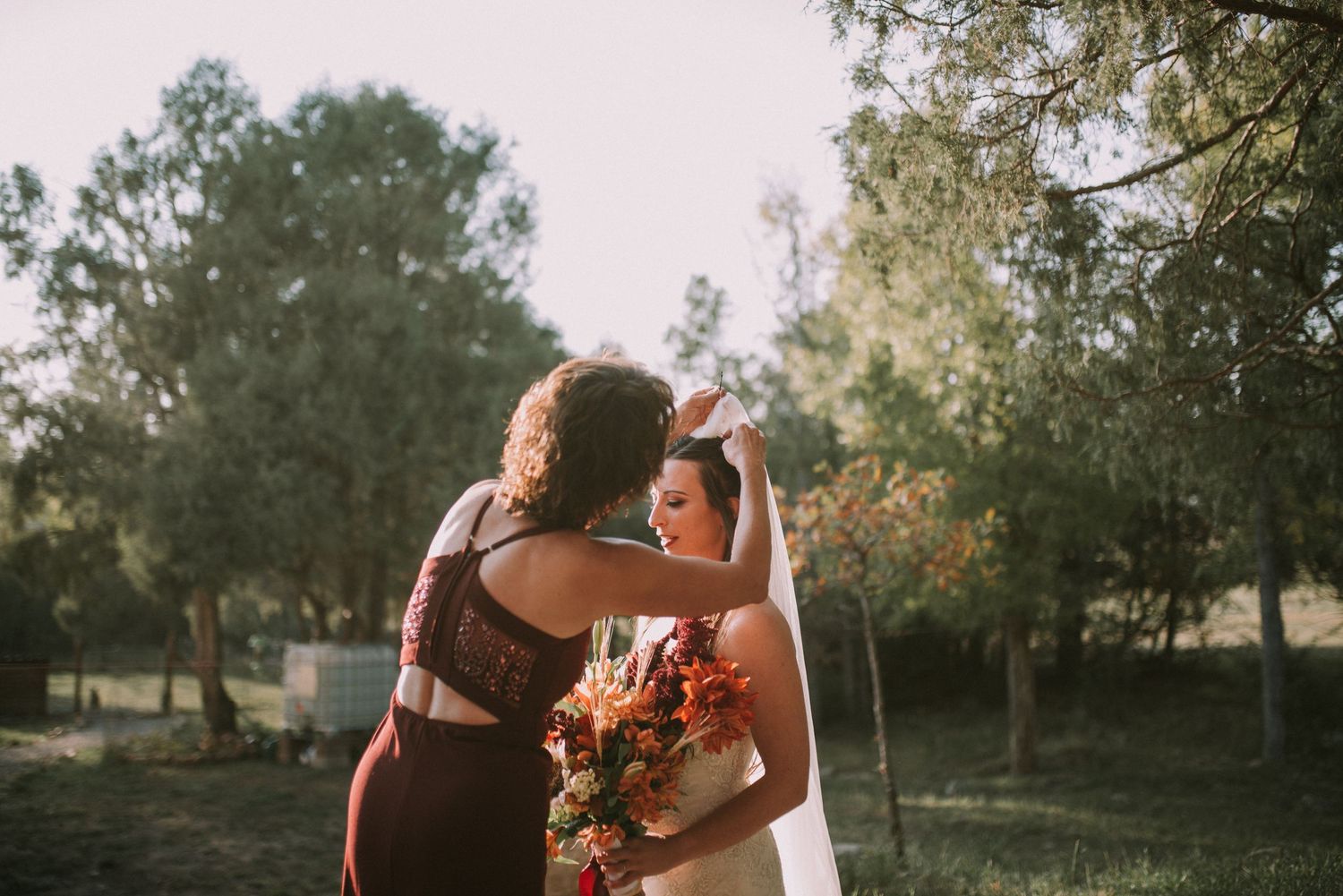 Wedding party sharing an intimate moment outdoors with autumn trees in background.