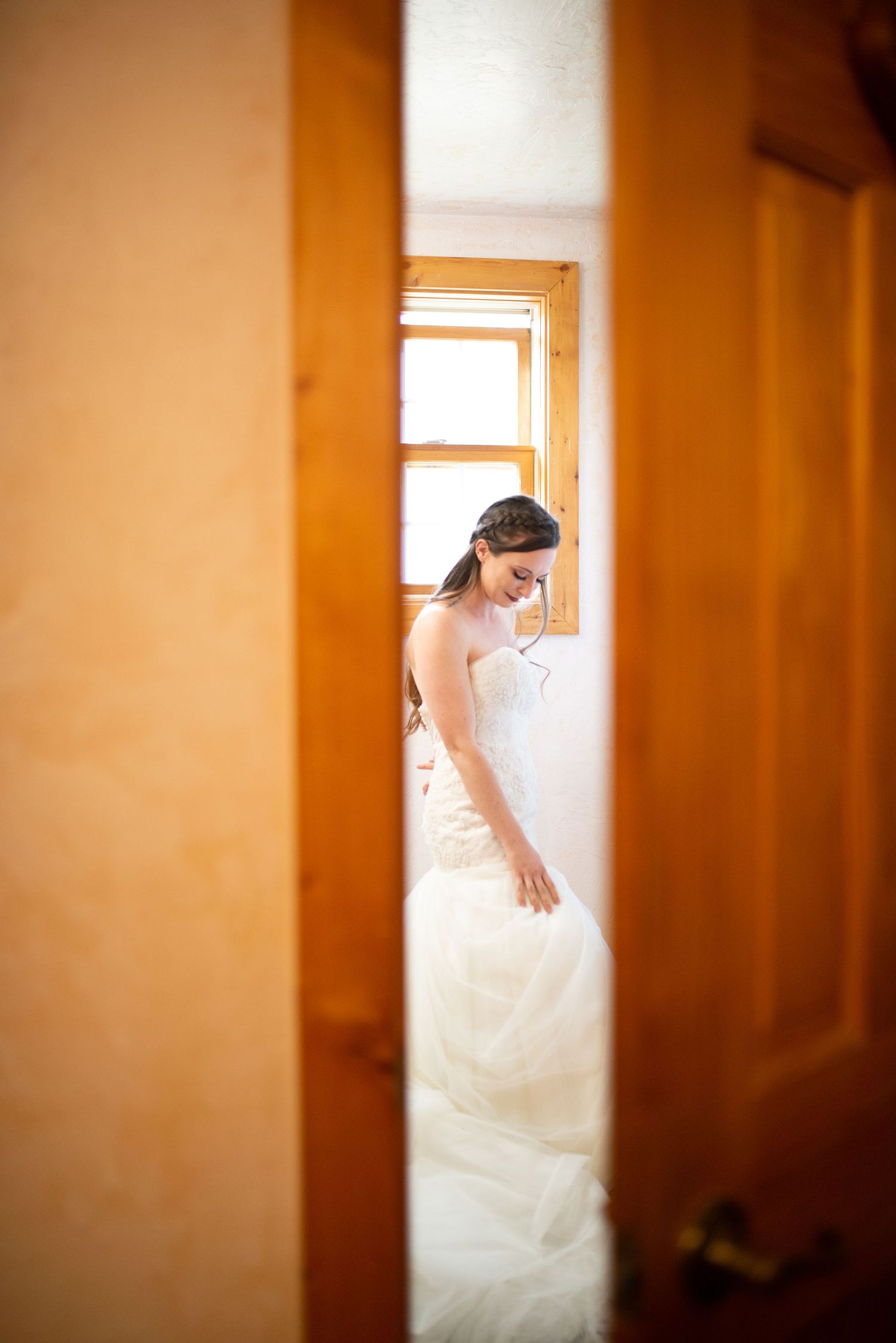 Artistic wedding photo showing bridal gown through partially opened doorway with soft focus.