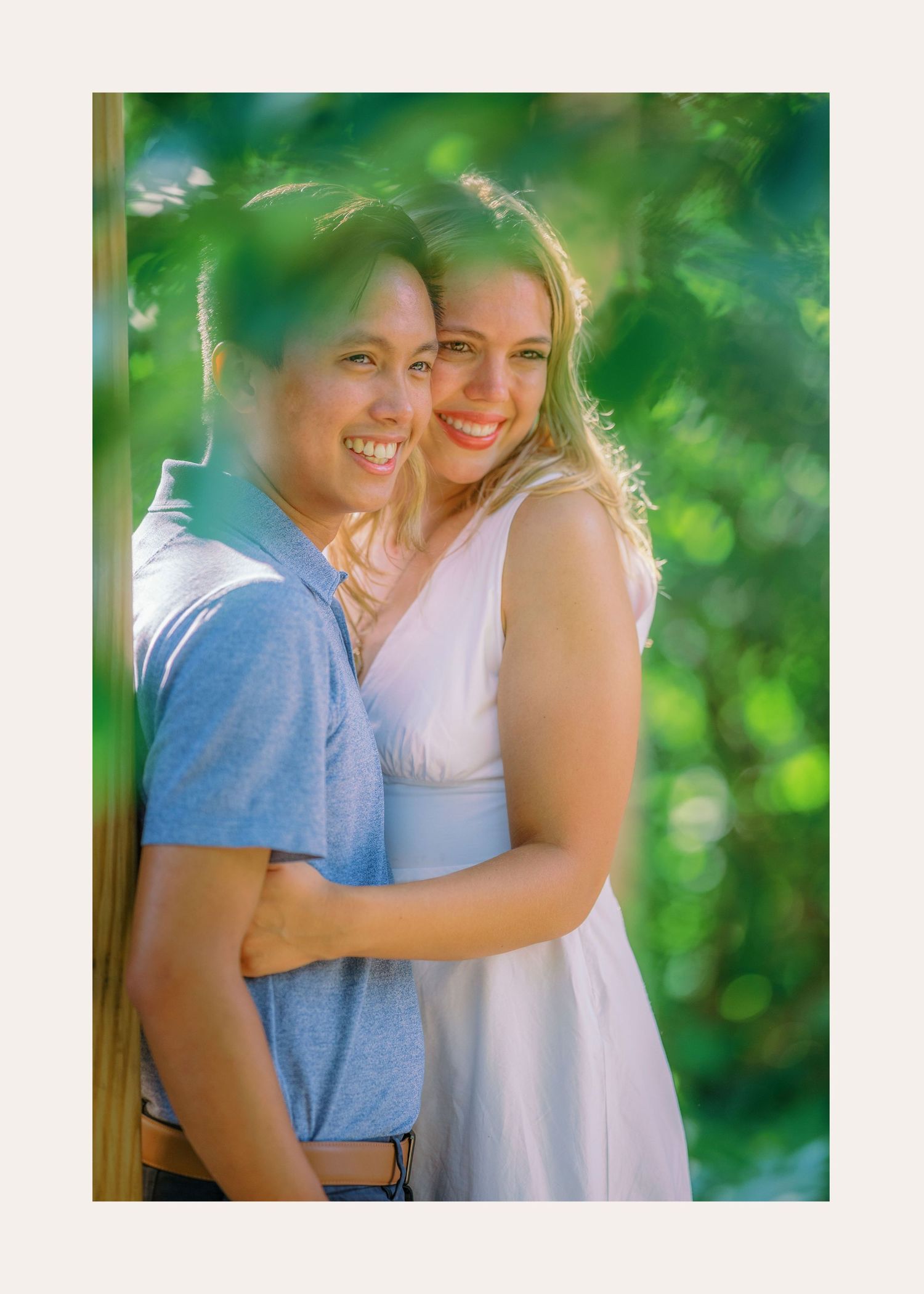 Romantic outdoor couple shoot with soft green bokeh background and natural lighting at sunset.