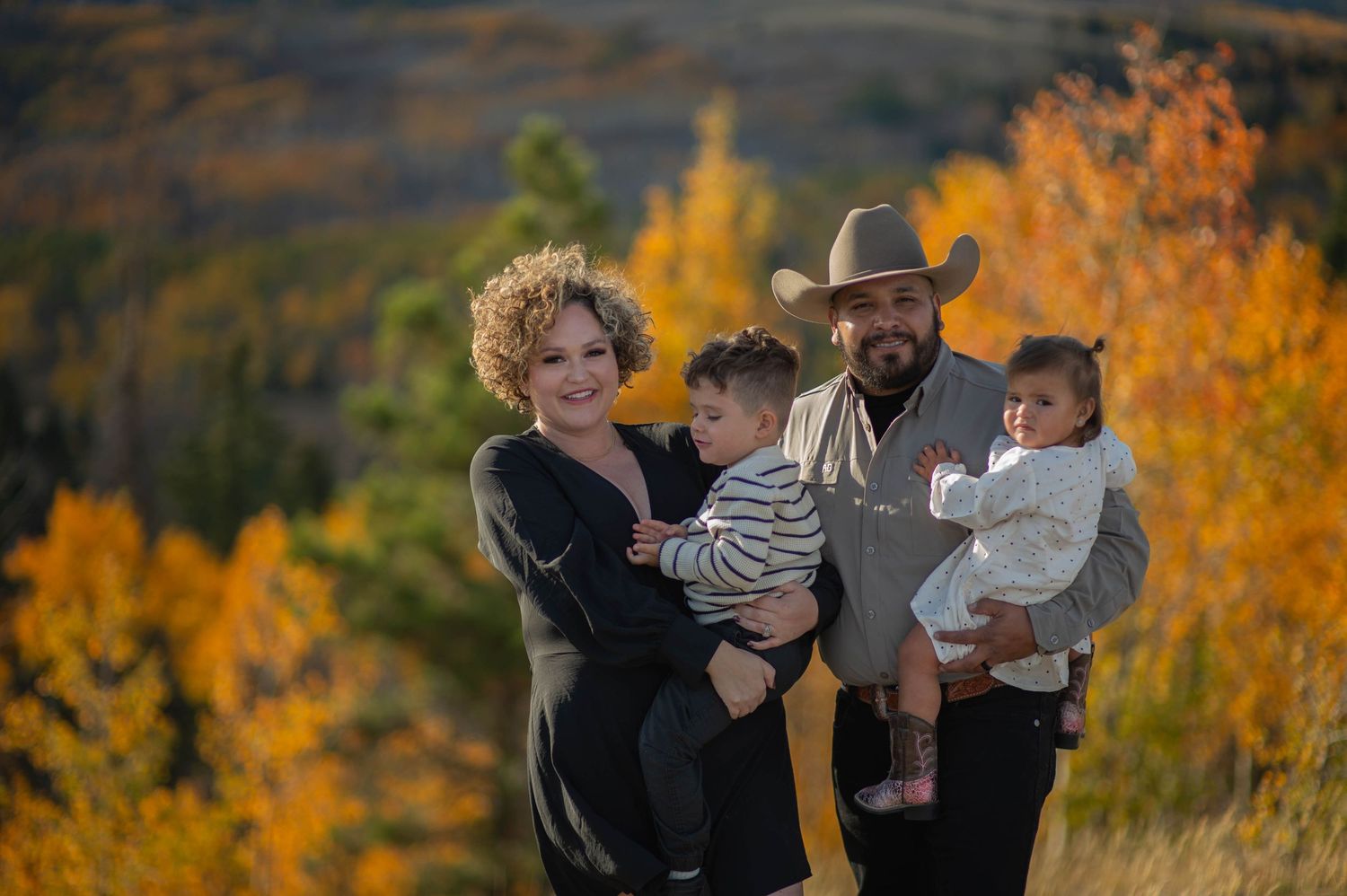 A happy family enjoys an autumn day together against vibrant fall foliage in the mountains.