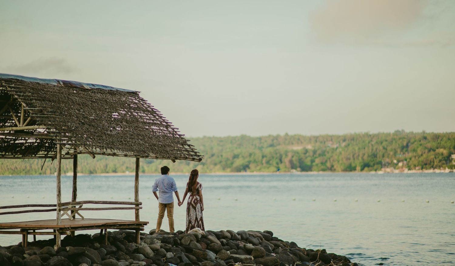 A scenic beach location with a wooden structure and palm trees overlooking the water.