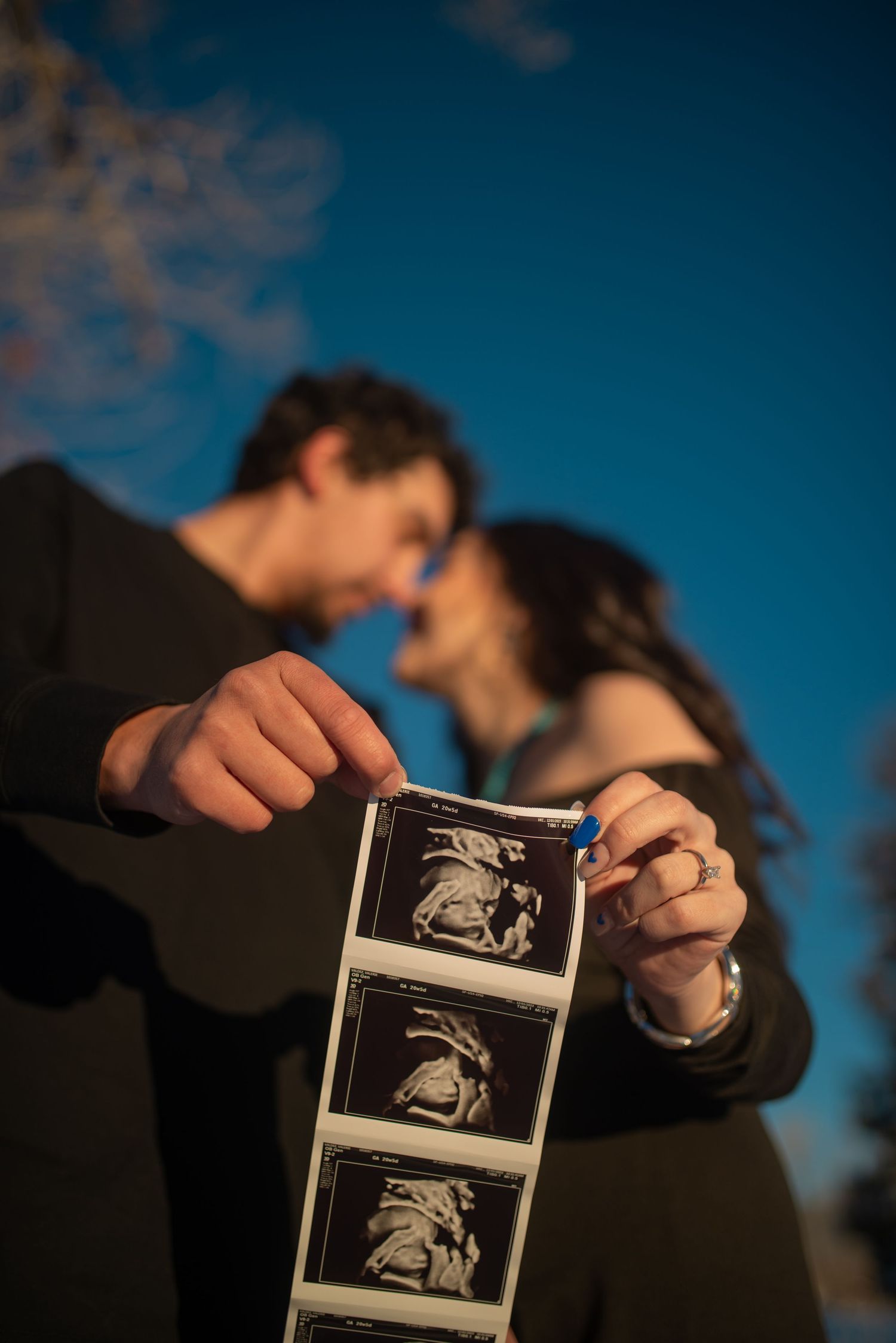 Close-up of hands holding an ultrasound image during a rustic maternity shoot near Santa Fe —