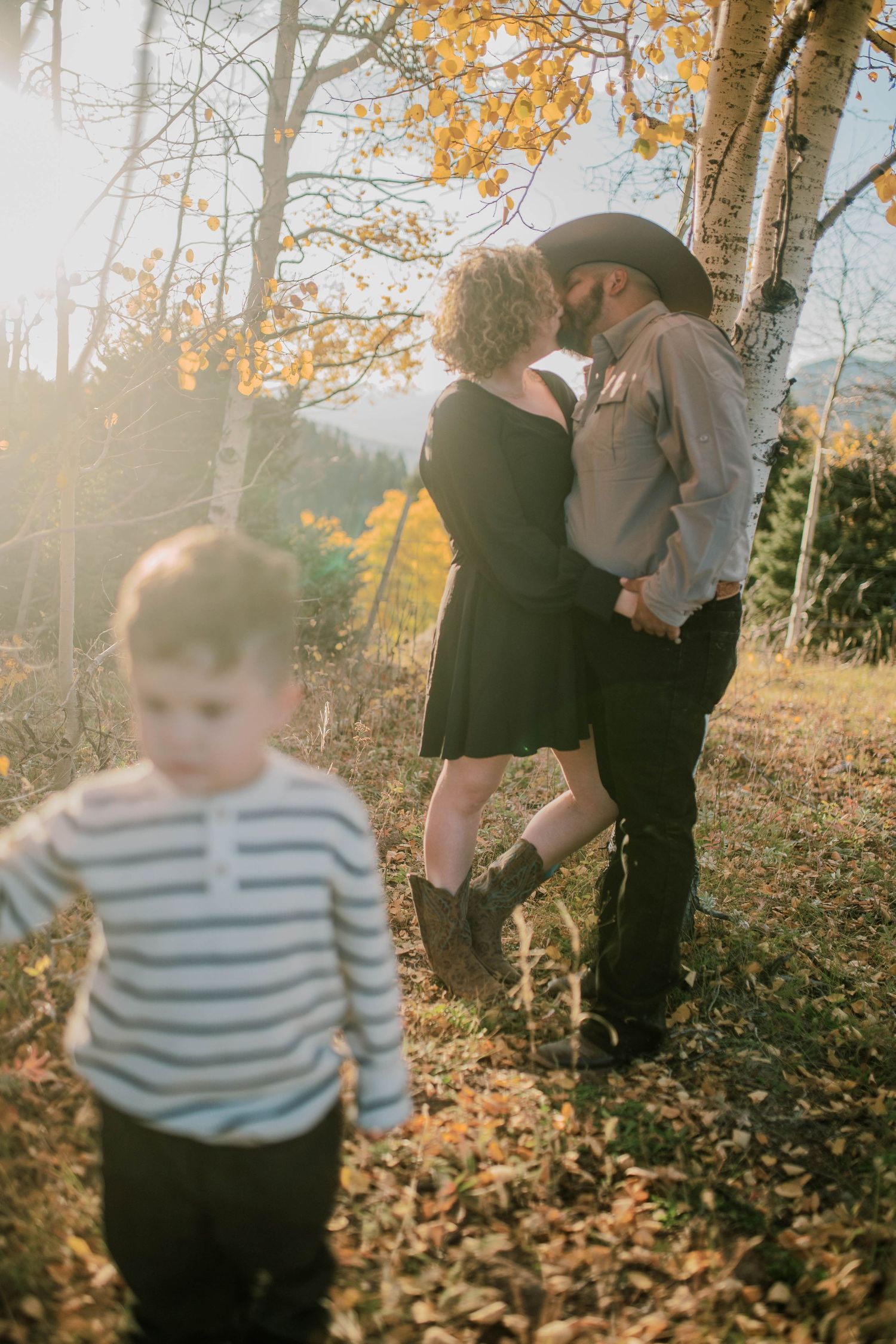 Family autumn photoshoot among fallen leaves and trees at sunset.