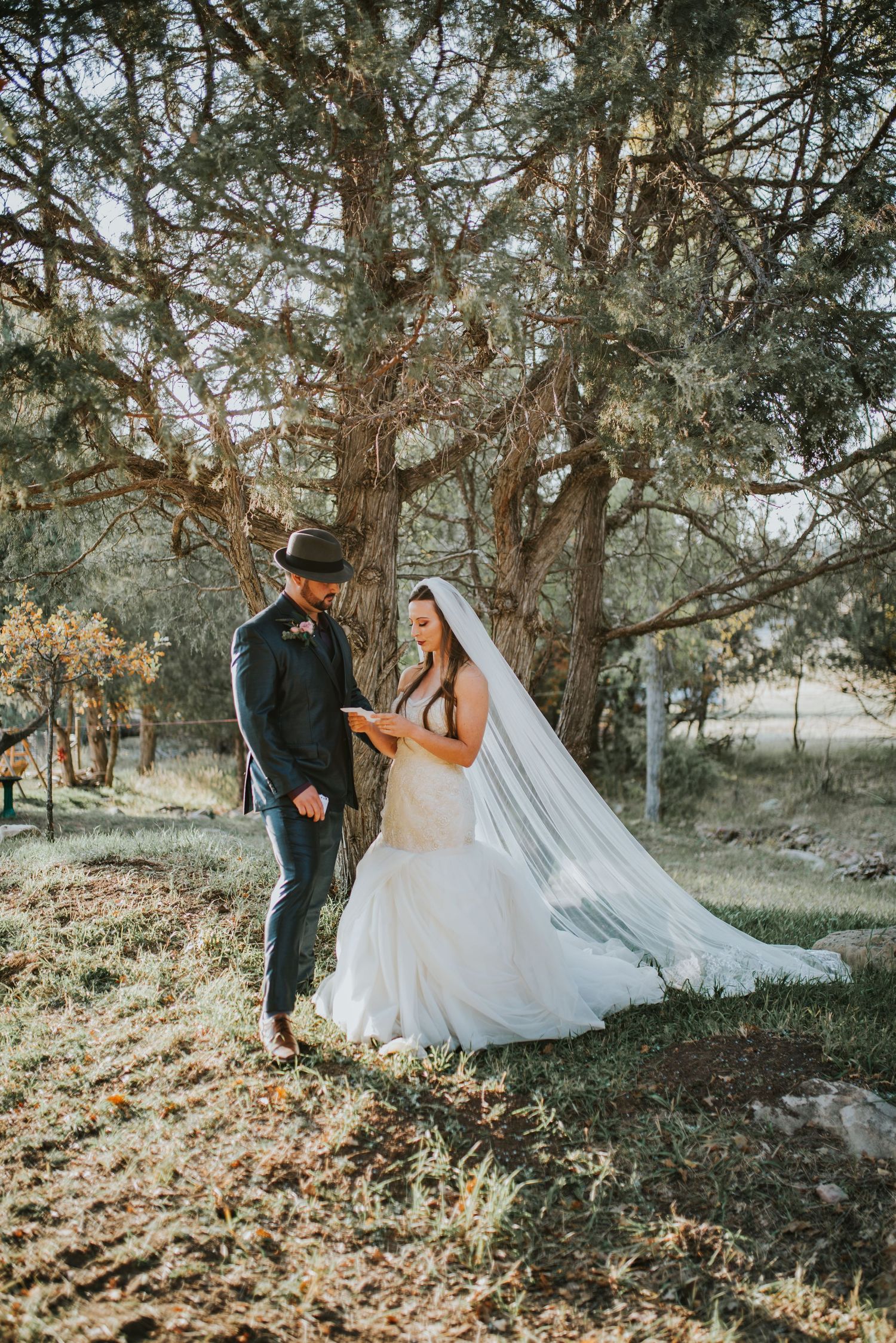 Bride and groom share an intimate moment under pine trees during their autumn wedding.