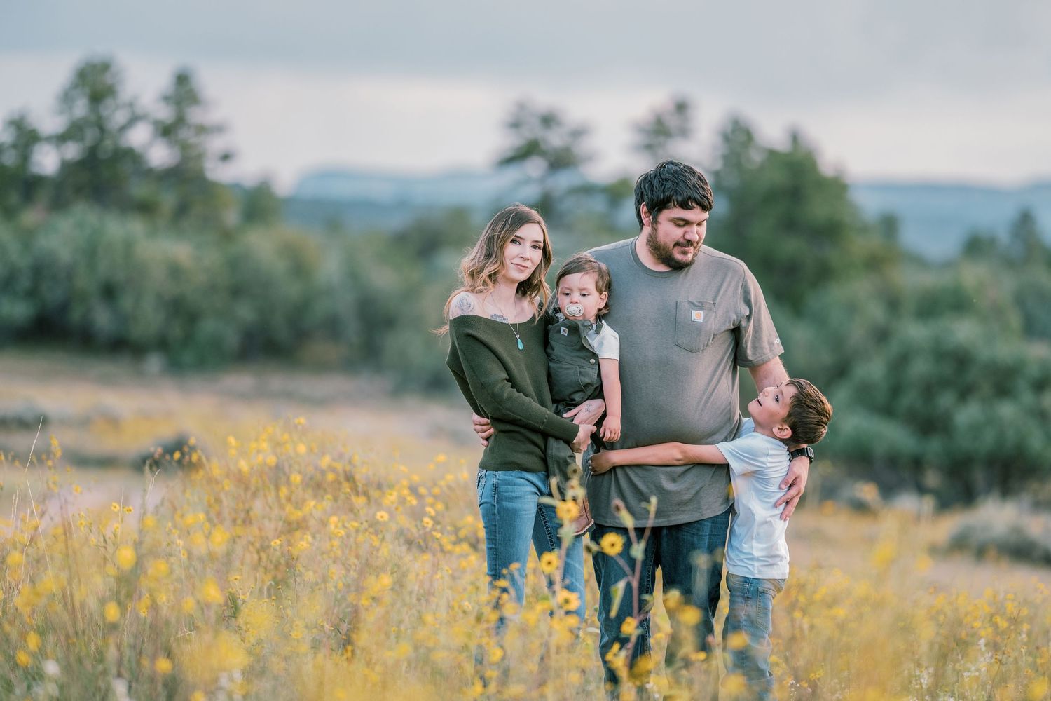 Family playing together in a blooming meadow with mountains on the horizon.