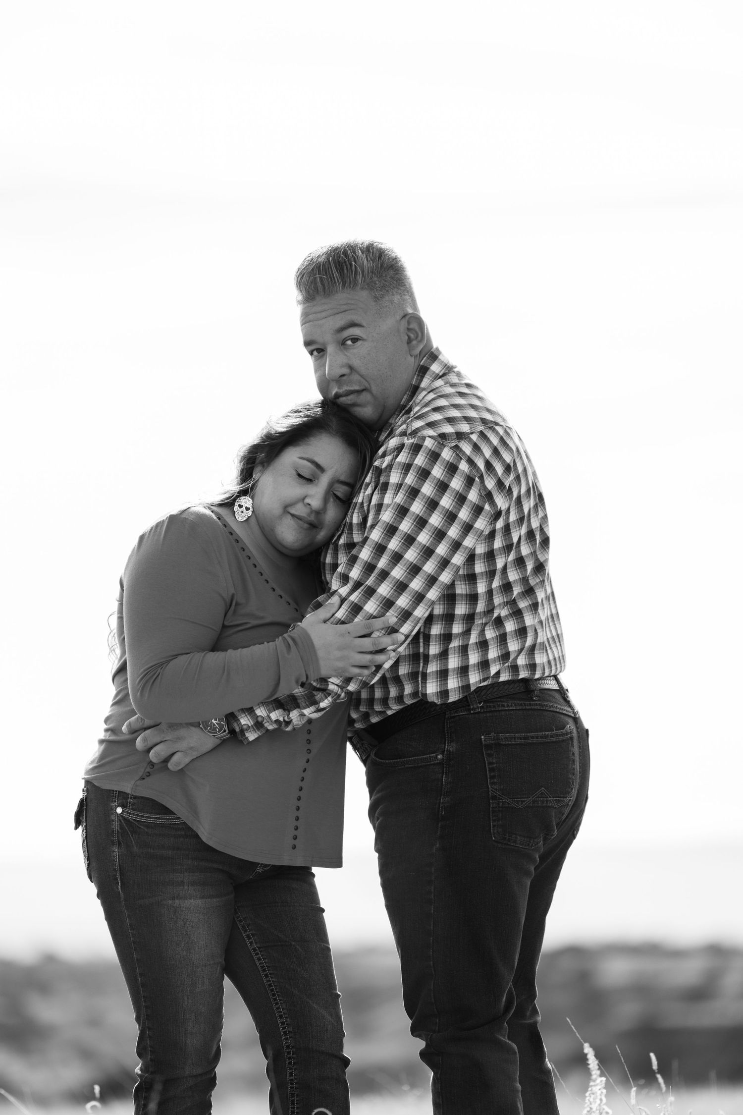Black and white portrait of an affectionate couple embracing outdoors, wearing casual clothing and jeans.