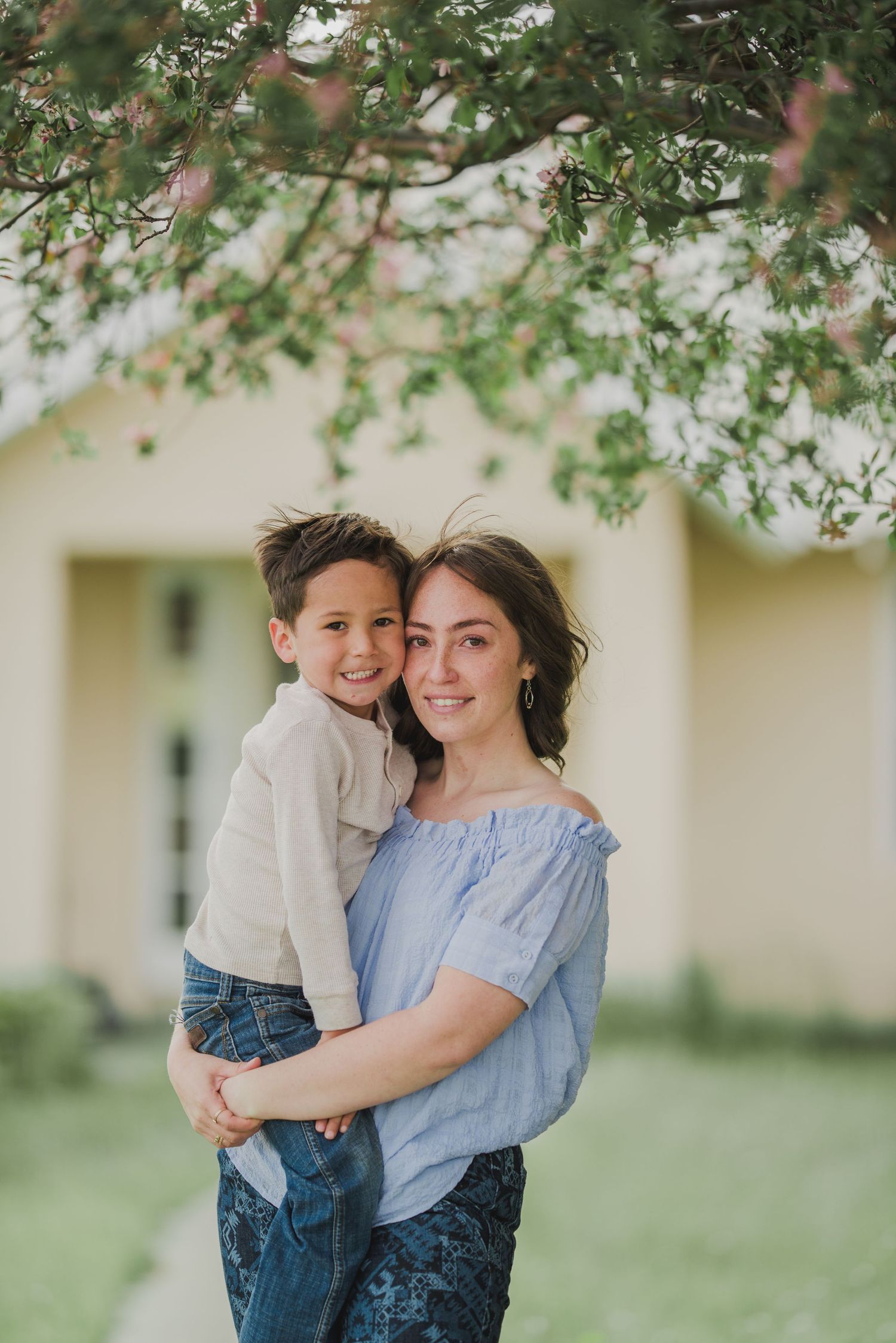 Mother and toddler sharing a quiet moment under a green tree — captured in natural light by The Amoras.
