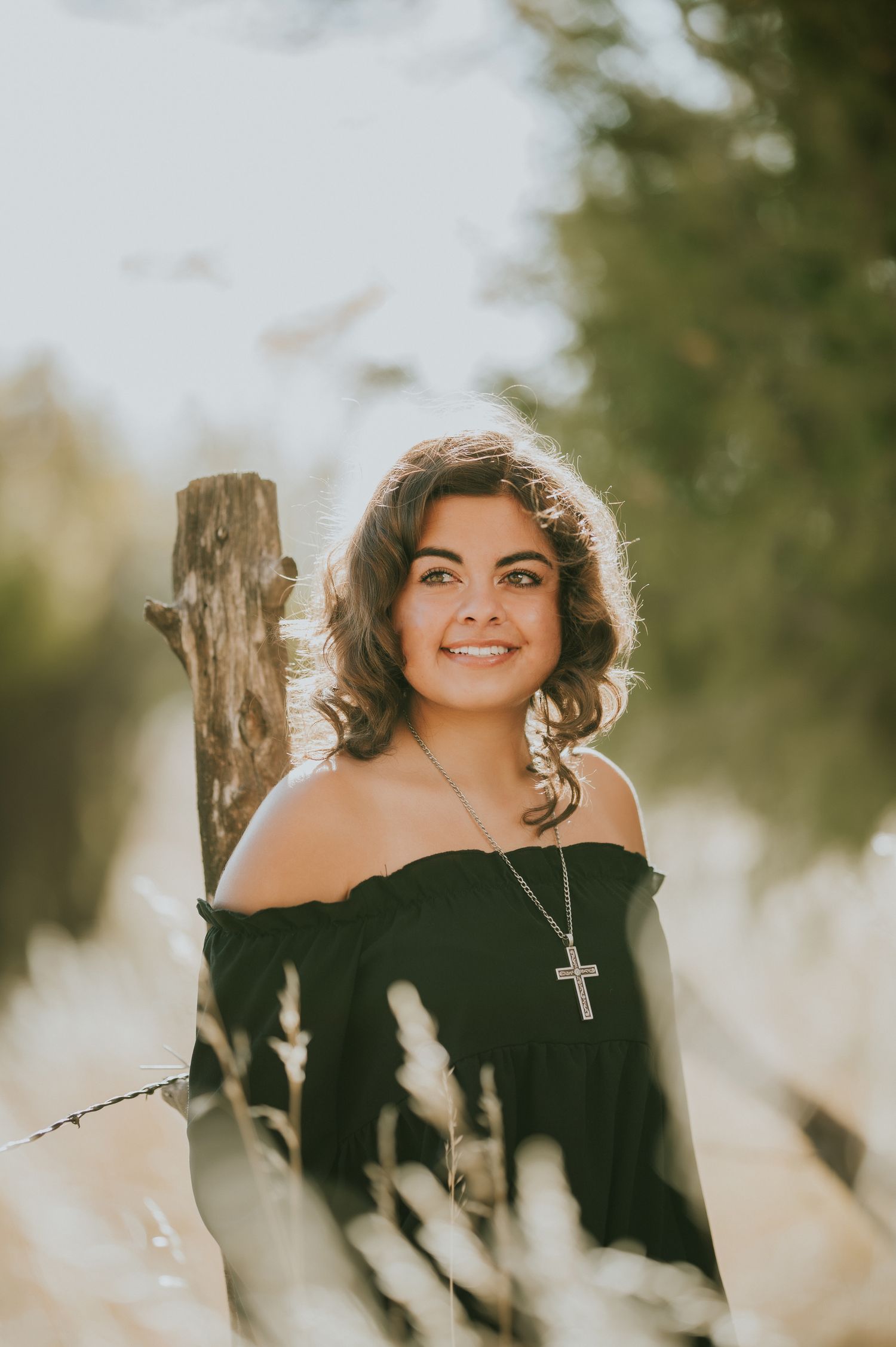 Artistic portrait shot through sunlit foliage with natural backlighting.