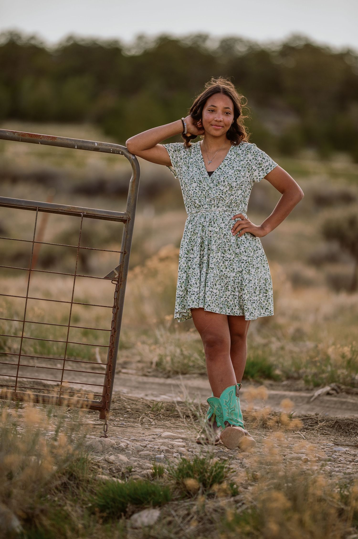 Series of candid shots showing a person in a floral dress posing against a rustic fence in an outdoor desert setting at dusk.