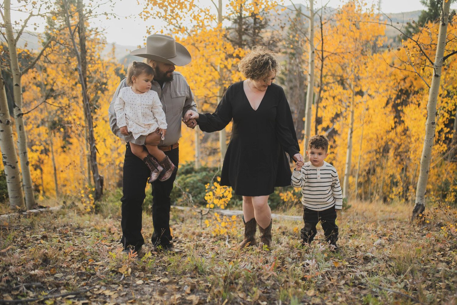 Family walking hand in hand through an autumn forest in northern New Mexico — warm storytelling photo by Quiet Light by The Amoras.