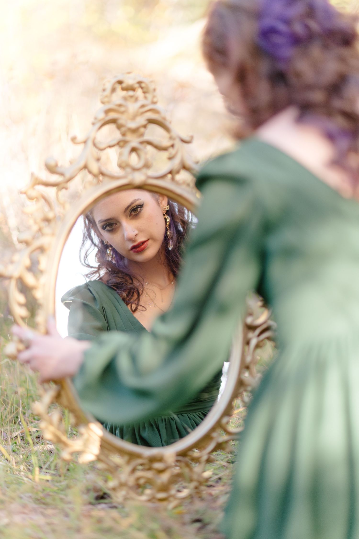 A dreamy reflection in an ornate vintage mirror shows a soft green dress and blurred floral background.