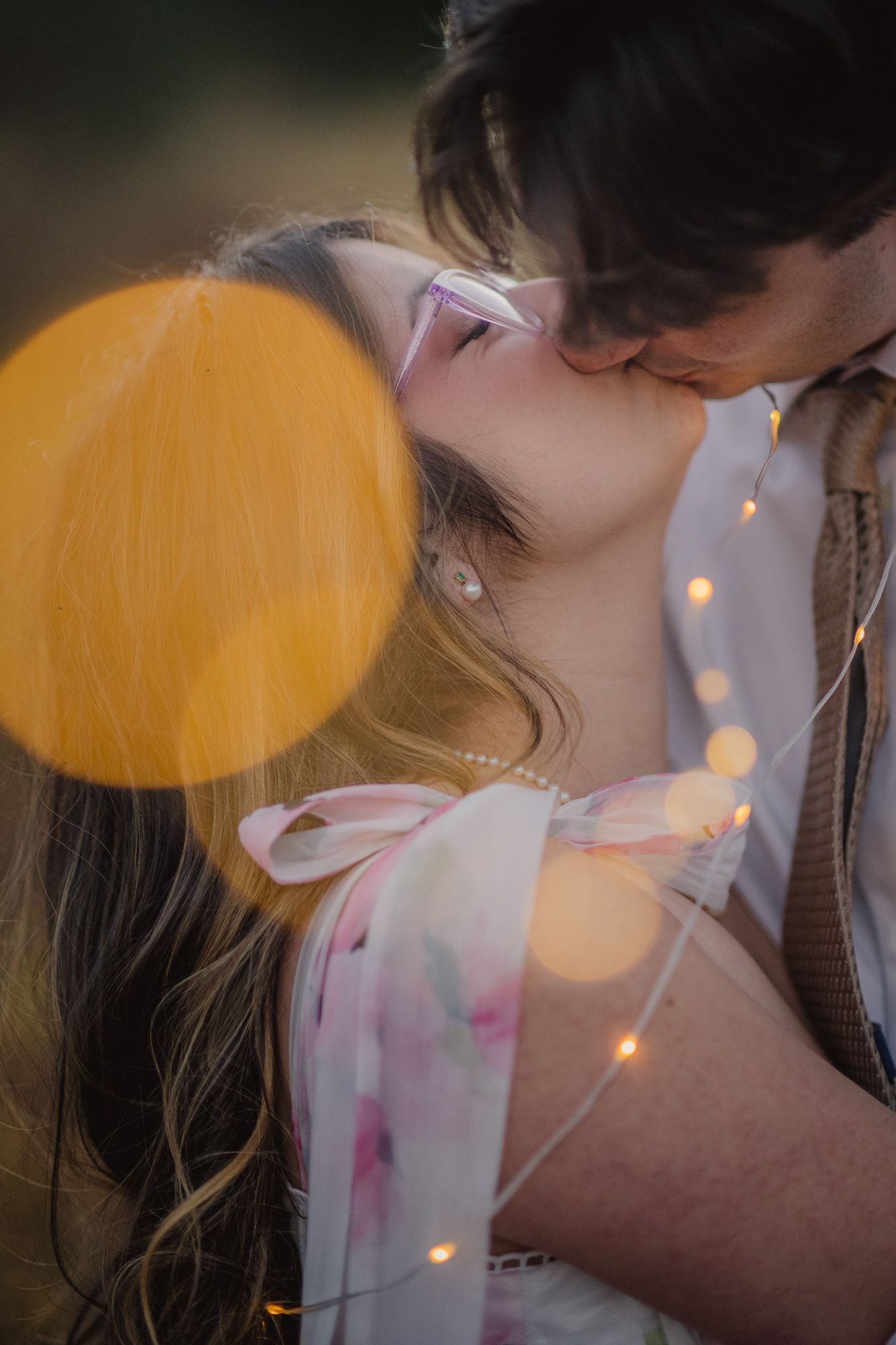 Couple kissing under glowing fairy lights at an evening engagement session in Chama, New Mexico.