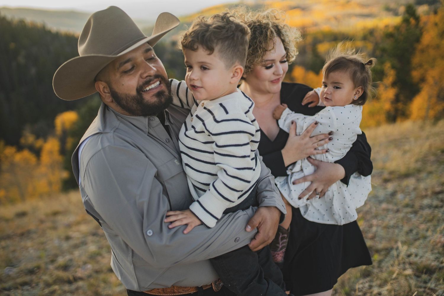 Cozy outdoor family photos during golden hour featuring parents and children against an autumn mountainside backdrop.