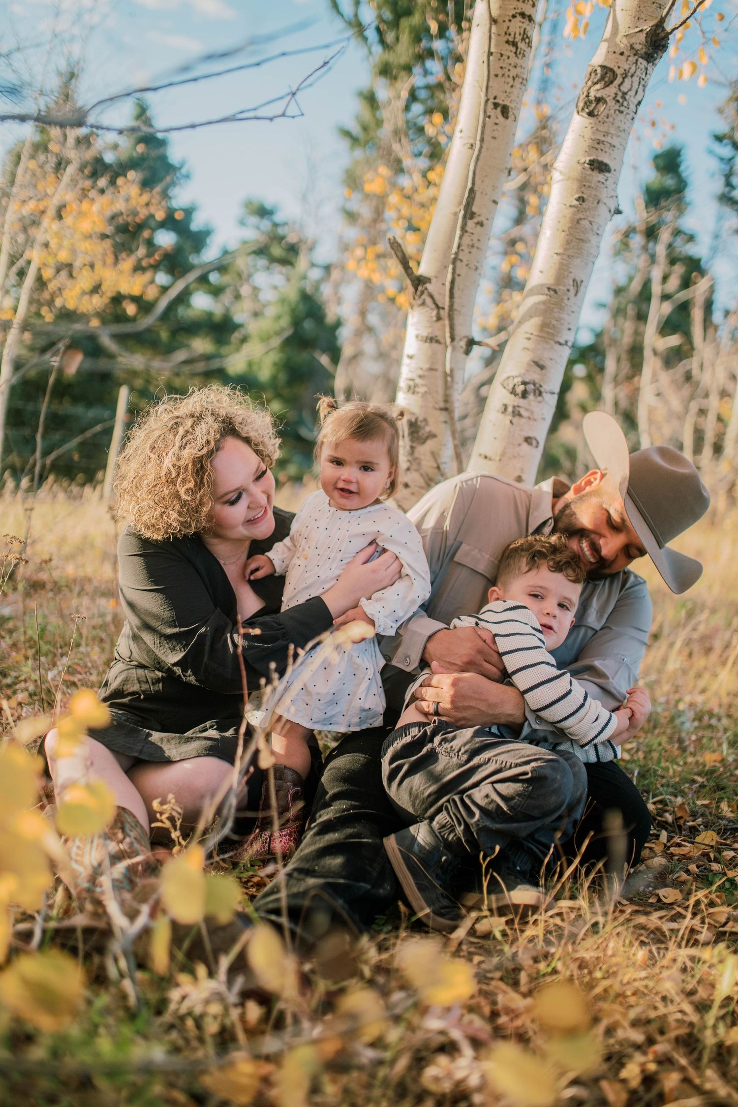Candid portrait of a family of four among fall trees — natural and heartfelt photo in northern New Mexico by The Amoras.